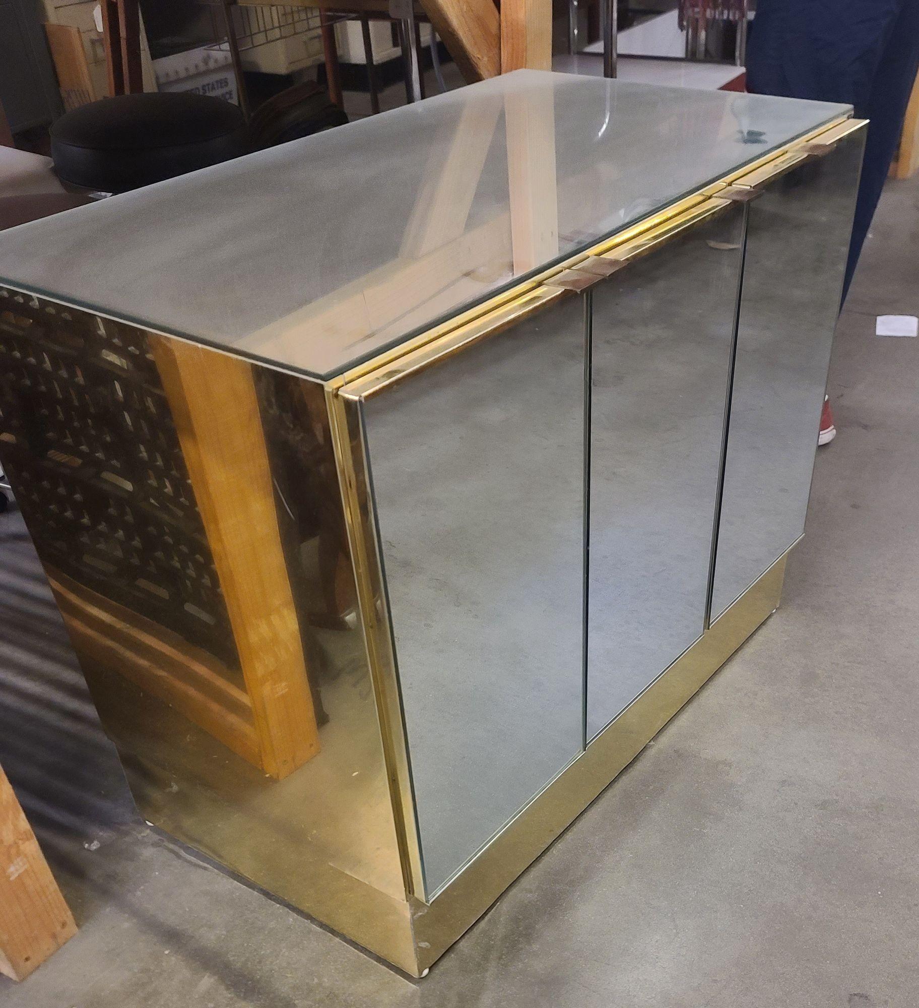 A 1970's postmodern bronze and polished metal mirror cabinet by Ello featuring three-panel mirror doors and a big interior storage space. There are some dings and a small amount of pitting on the metal, but the wear of the piece (consistent with