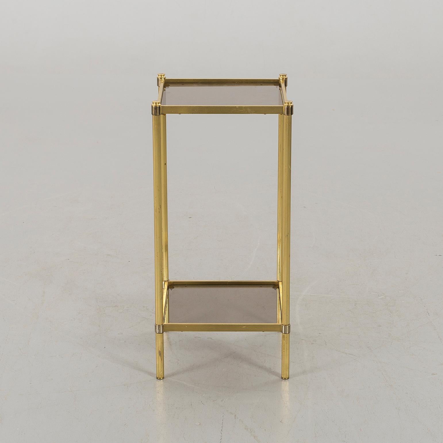 A brass and two-tiered smoked glass tops shelves side table
Sweden, circa 1970.