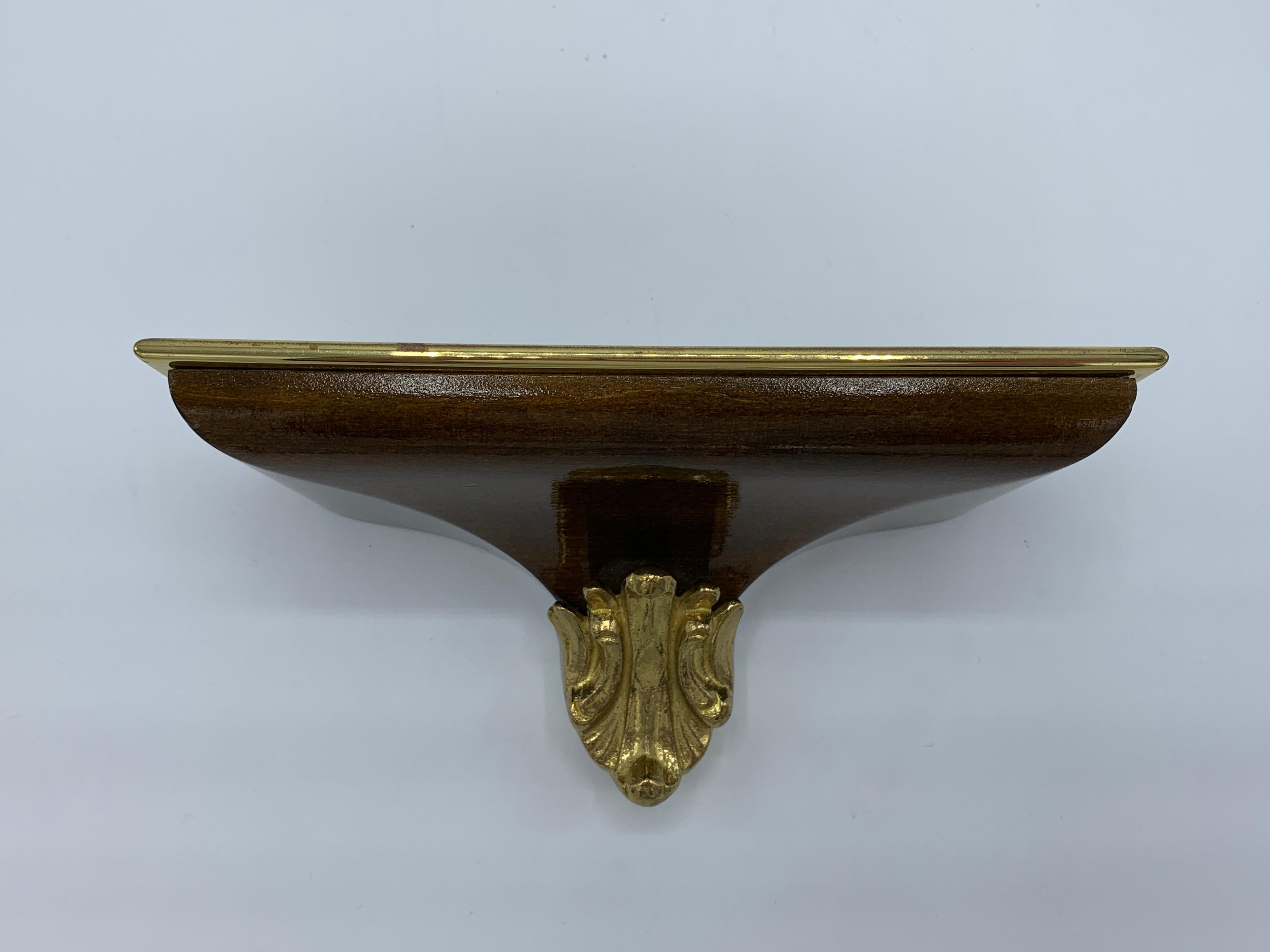 Listed is a stunning, 1970s polished-brass and walnut wall bracket shelf. The piece is small, but has a large presence with it’s scale. Heavy, weighing 1.5lbs.