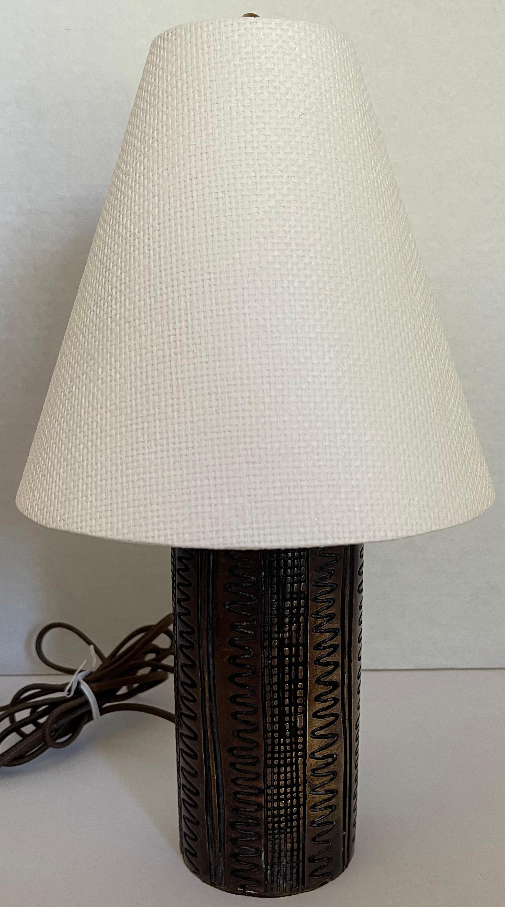 1970s burnished brass petite table lamp. All over carved geometric design. Newly rewired with new brass socket. Lamp takes one standard bulb (not included). Custom white Phillip Jeffries grasscloth lampshade by Illume NYC is included. Bulb clip and