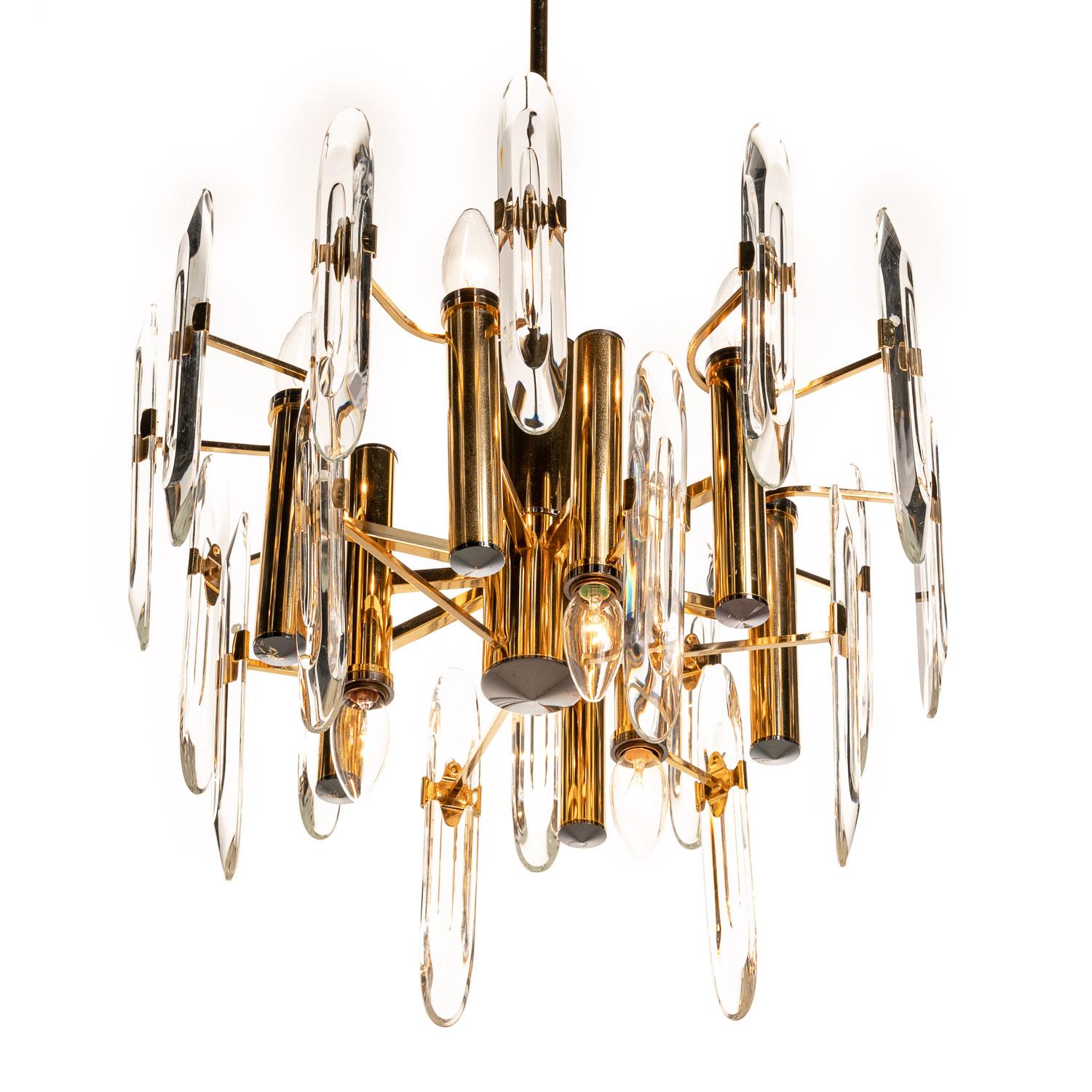 Classic 1970s Italian Gaetano Sciolari design chandelier with characteristic use of crystal glass and layered tiers on a brass frame. It holds nine E14 lights of which three facing down.