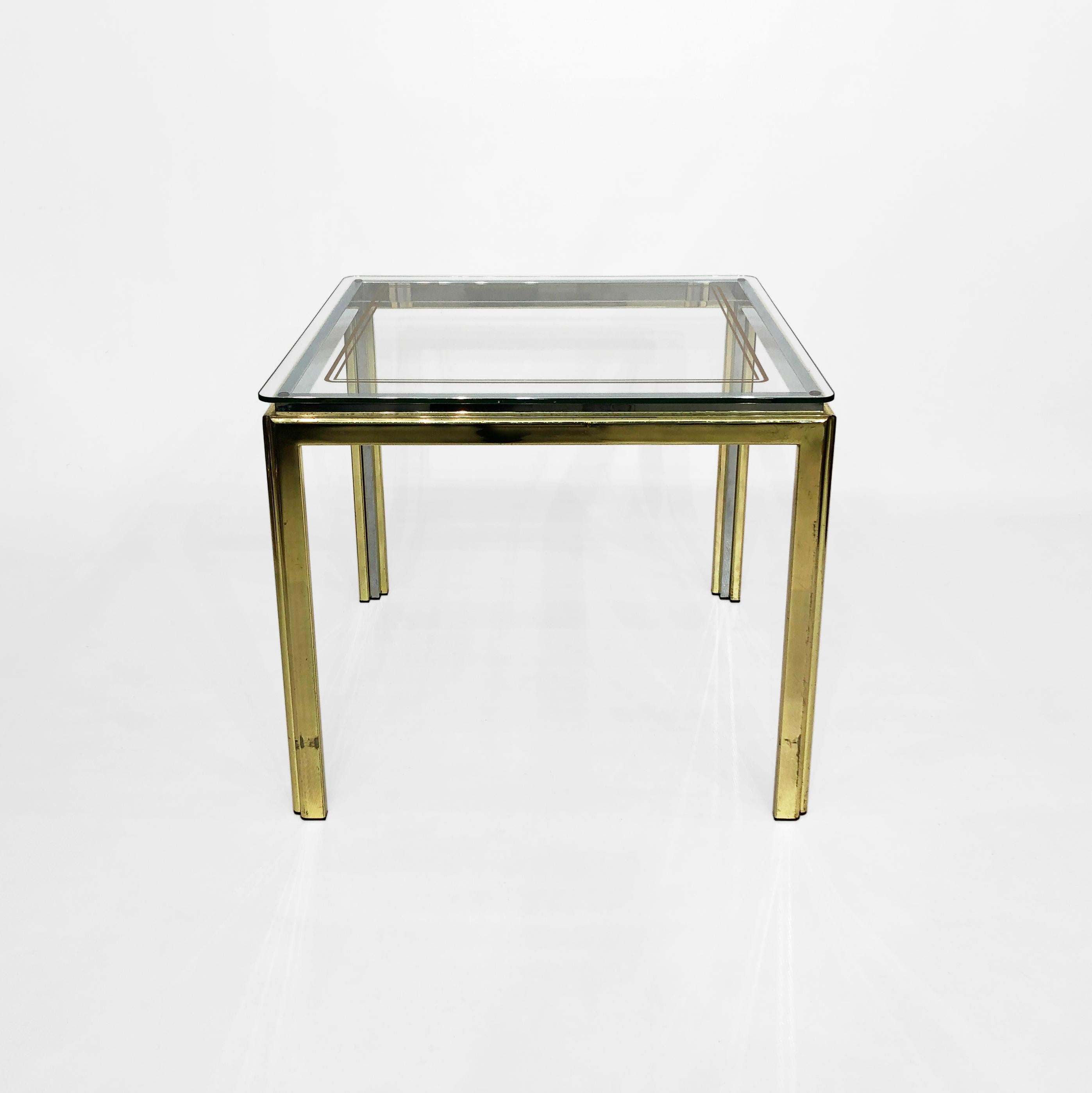 A vintage side table with brass plating external frame and an inner elevated chrome frame that supports the glass top, a stylish and practical piece of furniture. The combination of brass and chrome creates a striking contrast that can add a touch
