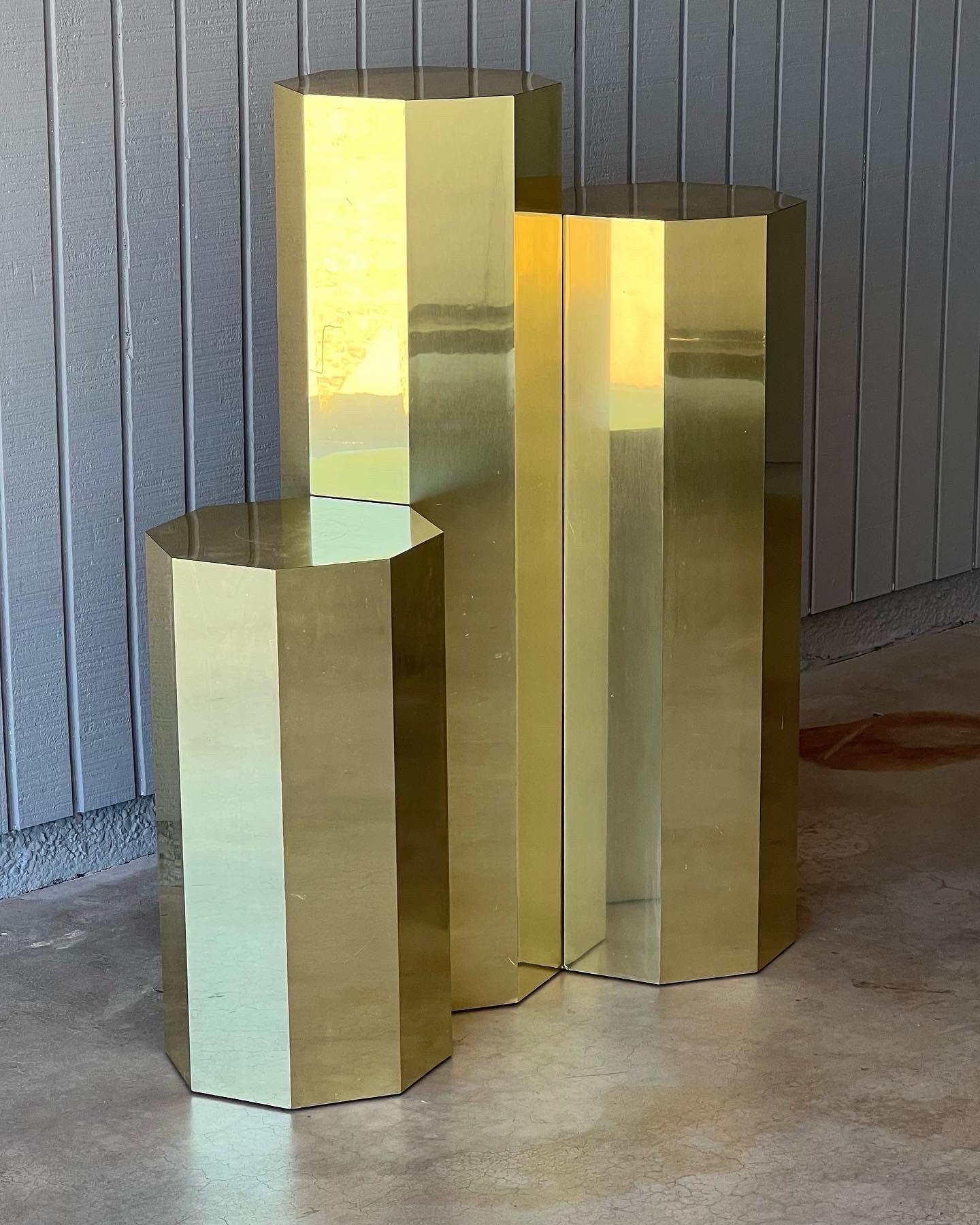 Set of three vintage display pedestals, likely 1970s. Sold as a set but may consider selling individually. They are octagon in shape, brass clad over wood and show age-appropriate signs of wear such as surface scratches as pictured. They have an