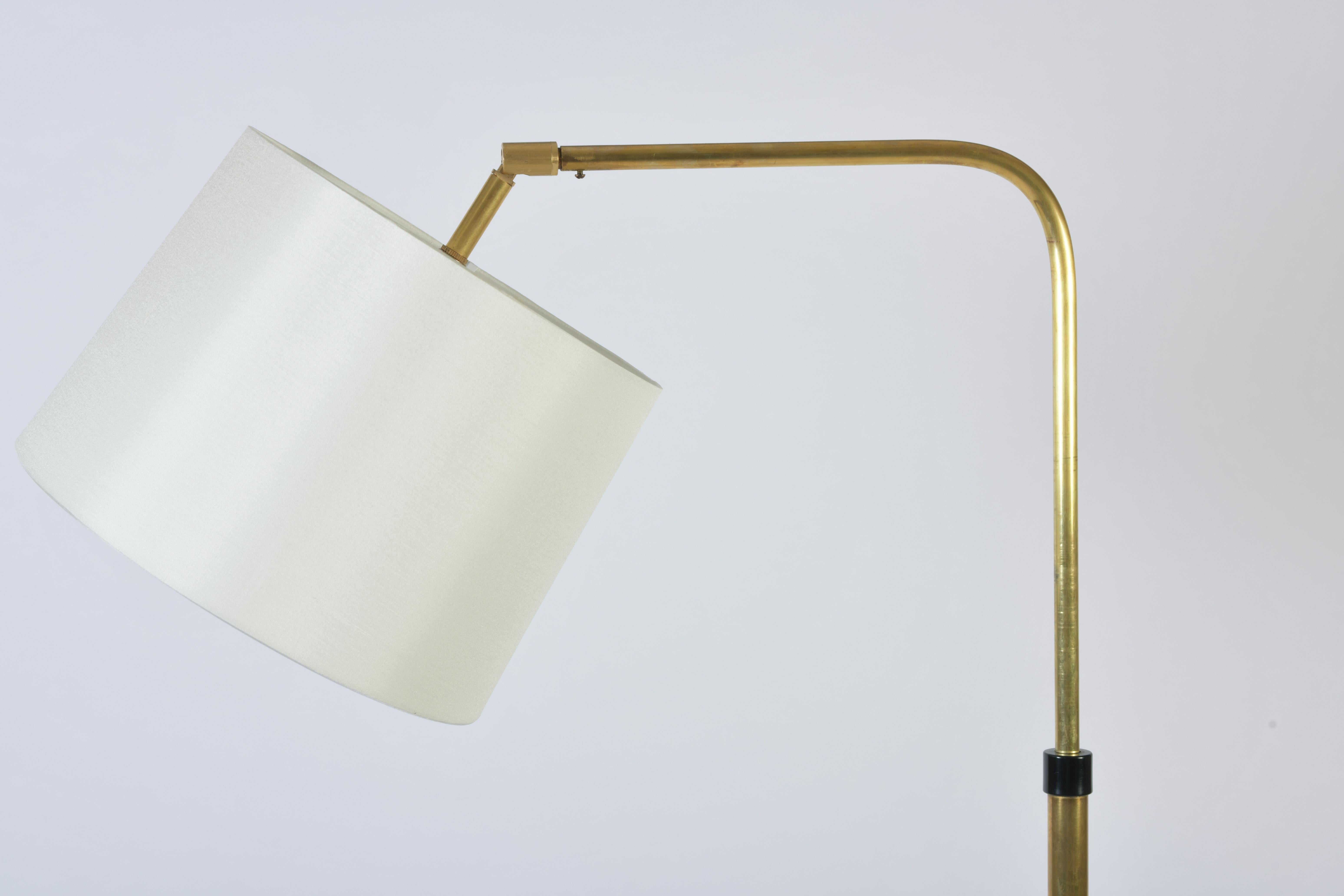 A telescopic brass floor lamp, with an adjustable light, in an ivory fabric drum shade
France, circa 1970.