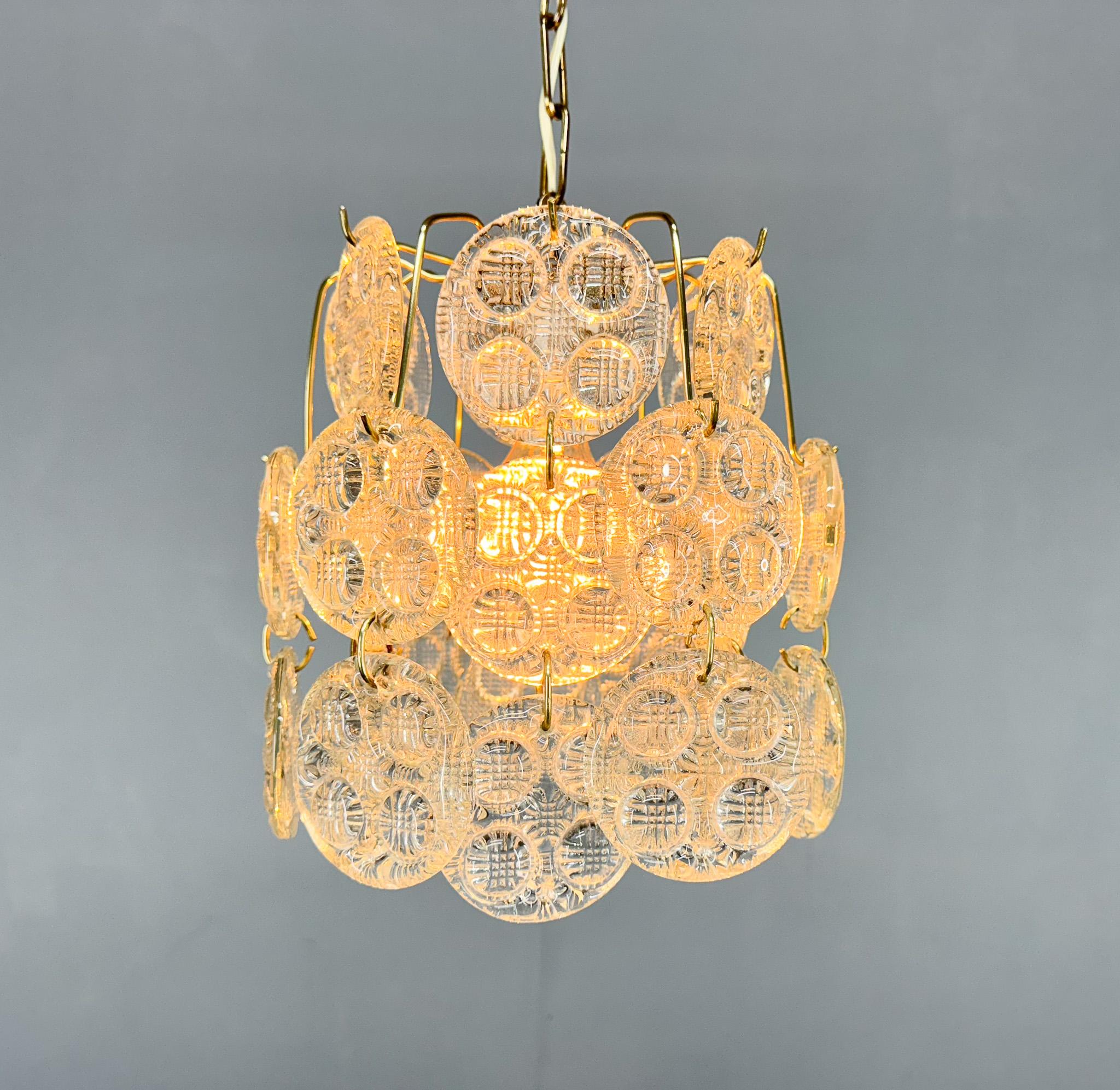 Un lampadario della metà del secolo scorso in ottone con ornamenti pendenti in vetro pressato realizzati in una vetreria locale degli anni '70. 
Lampadina: 1 x E27 (E26). Compatibile con il cablaggio degli Stati Uniti.