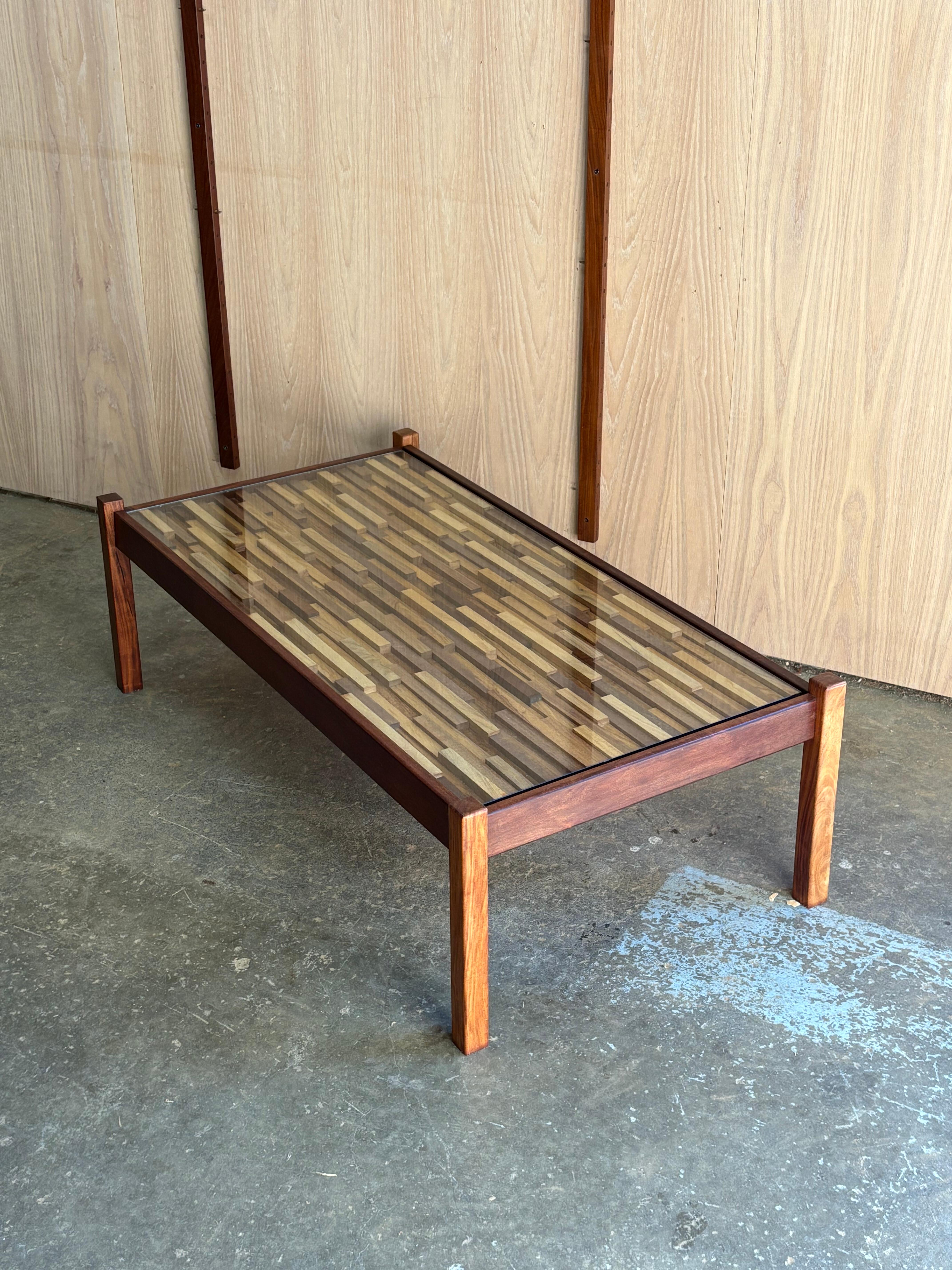 Table basse en bois dur brésilien des années 1970 de l'emblématique Percival Lafer, avec son incomparable plateau en mosaïque géométrique placé sous un verre épuré pour une touche d'élégance moderne. Le cadre en bois tropical riche a été fraîchement