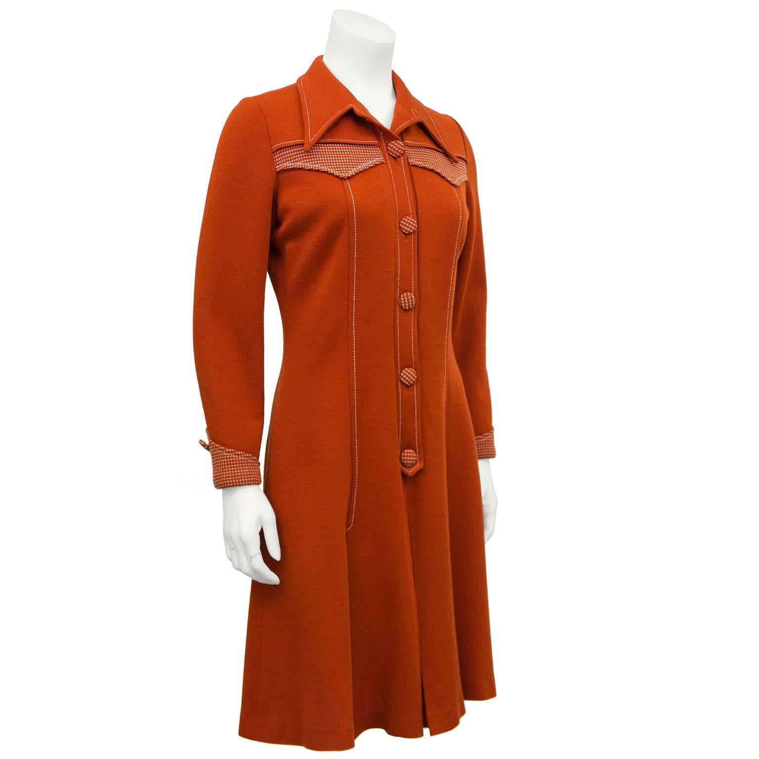 Brick red 'Cowboy' style dress from the 1970s with contrasting stitch detail. The wide, pointed lapel is accented with a contrasting double yoke at the bust line and single along the back. Vertical seams elongate the silhouette and the dress opens