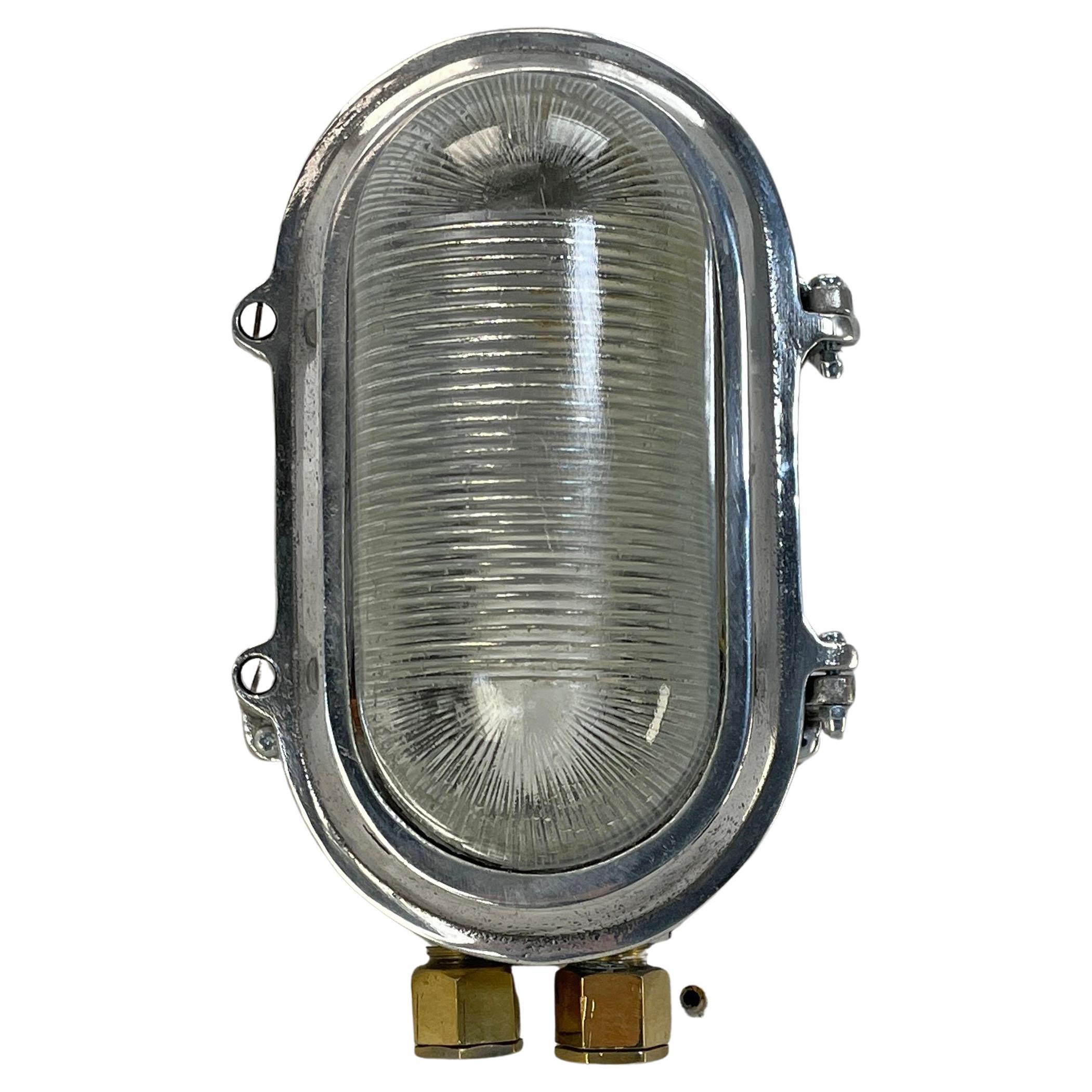 A vintage Industrial cast aluminium oval bulkhead wall light with prismatic reeded glass.

Originally marine lighting, this type of aluminium circular bulkhead is found on ship passageways. Professionally restored and rewired by Loomlight in UK