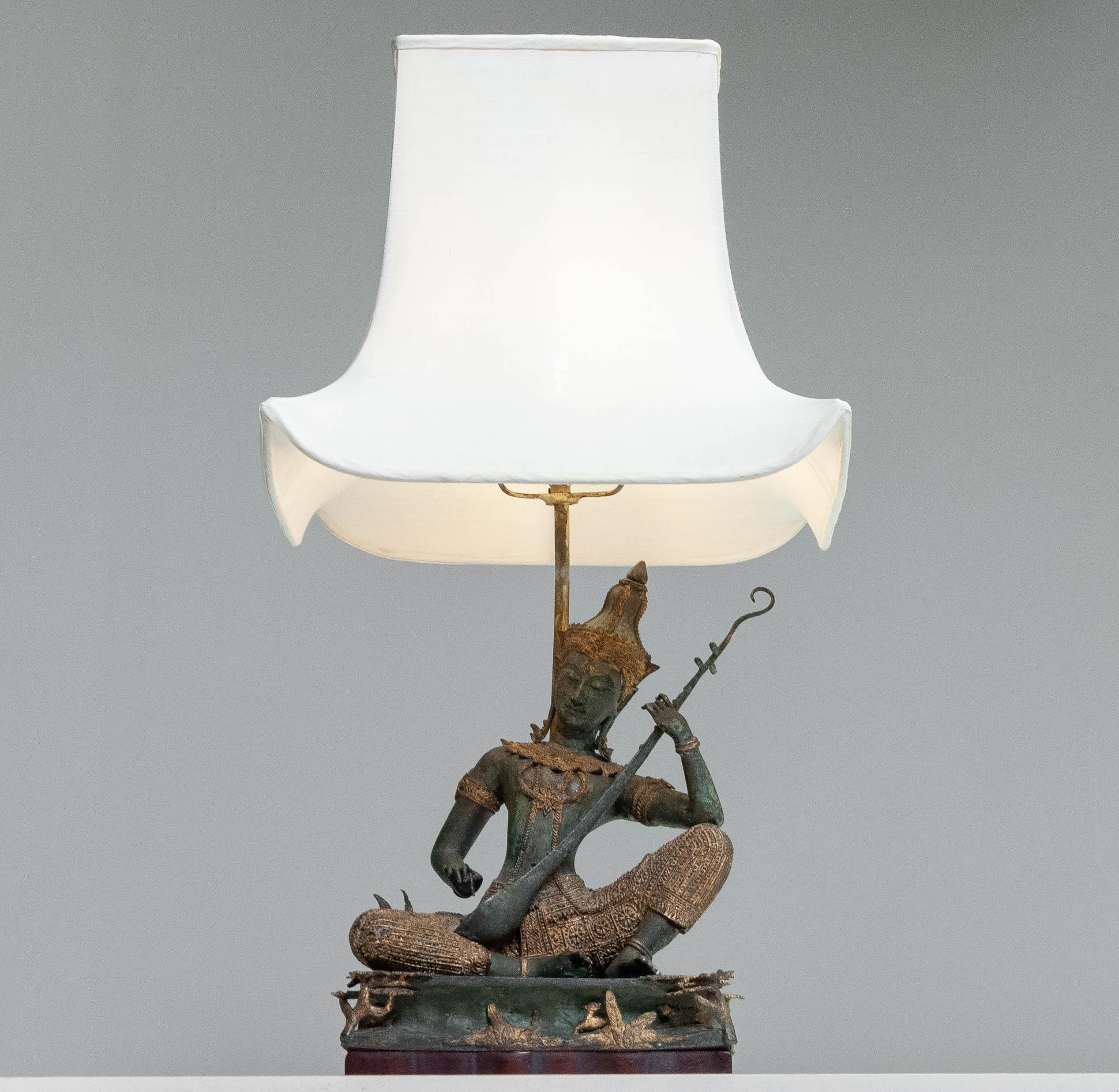 Una splendida lampada da tavolo in bronzo con un'intricata figura di musicista tailandese in posa seduta.

Materiale: Bronzo fuso con dettagli dorati
Design/One: Divinità tradizionali ispirate al sud-est asiatico che suonano uno strumento