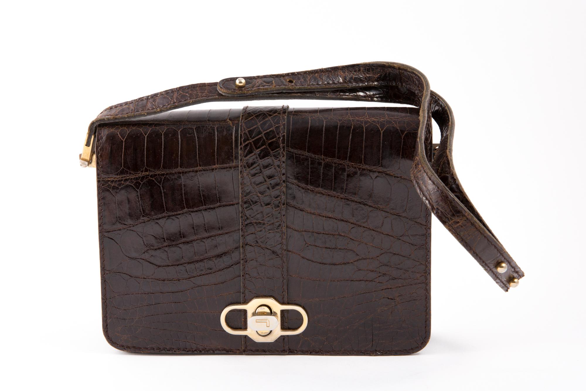 1970s brown leather hand bag featuring an adjustable hand strap, a front gold tone claps opening, inside compartments.
Length at Bottom 8.6in. (22 cm)
Height: 6.2in. (16 cm)
Width:2.7in (7cm)
In good vintage condition.  Made in France.
Please note