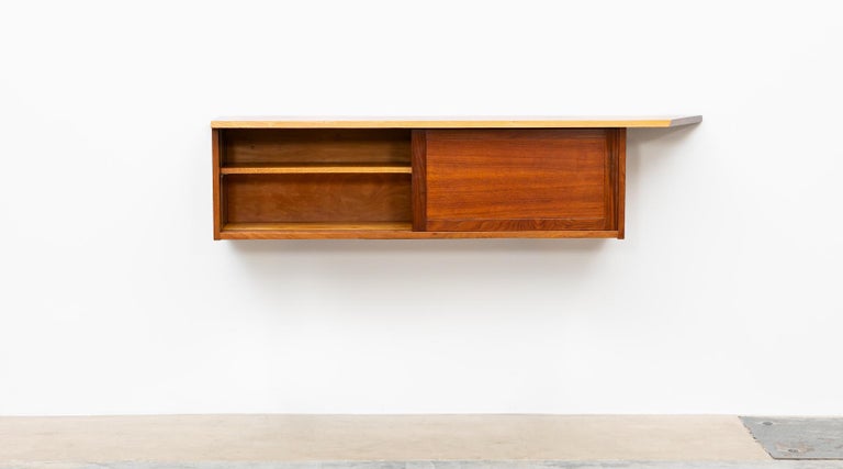 This handcrafted and wall-mounted sideboard by George Nakashima has a beautifully figured American black walnut slab top with an organic and subtle free-form edge. Comes with two sliding doors, containing three shelves. Manufactured by George
