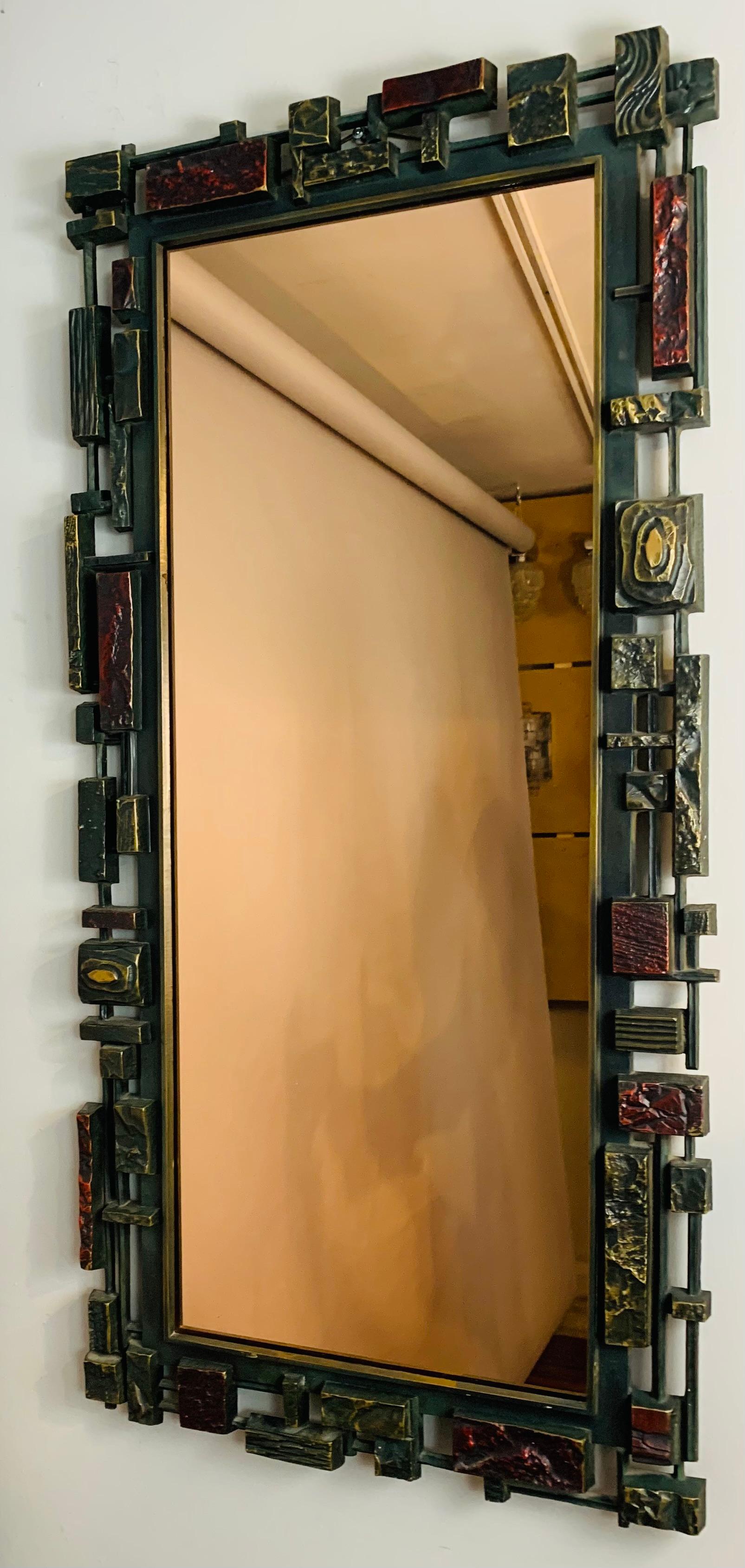 1970s rectangular hanging wall mirror manufactured by Syroco, USA. The unusual, abstract, frame is formed from an injection moulded textured thick resin plastic which is multi-coloured with a metallic finish in vibrant colours of gold and red. The