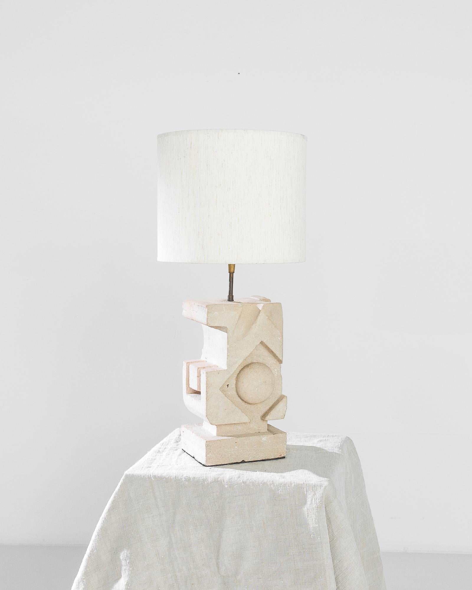 This sculptural lamp crafted in Belgium circa 1970 imparts the utopian spirit of brutalism. The monolithic base carved out of a solid stone block features bold geometric structures, gently smoothed by the tender color palette —rosewater pink with