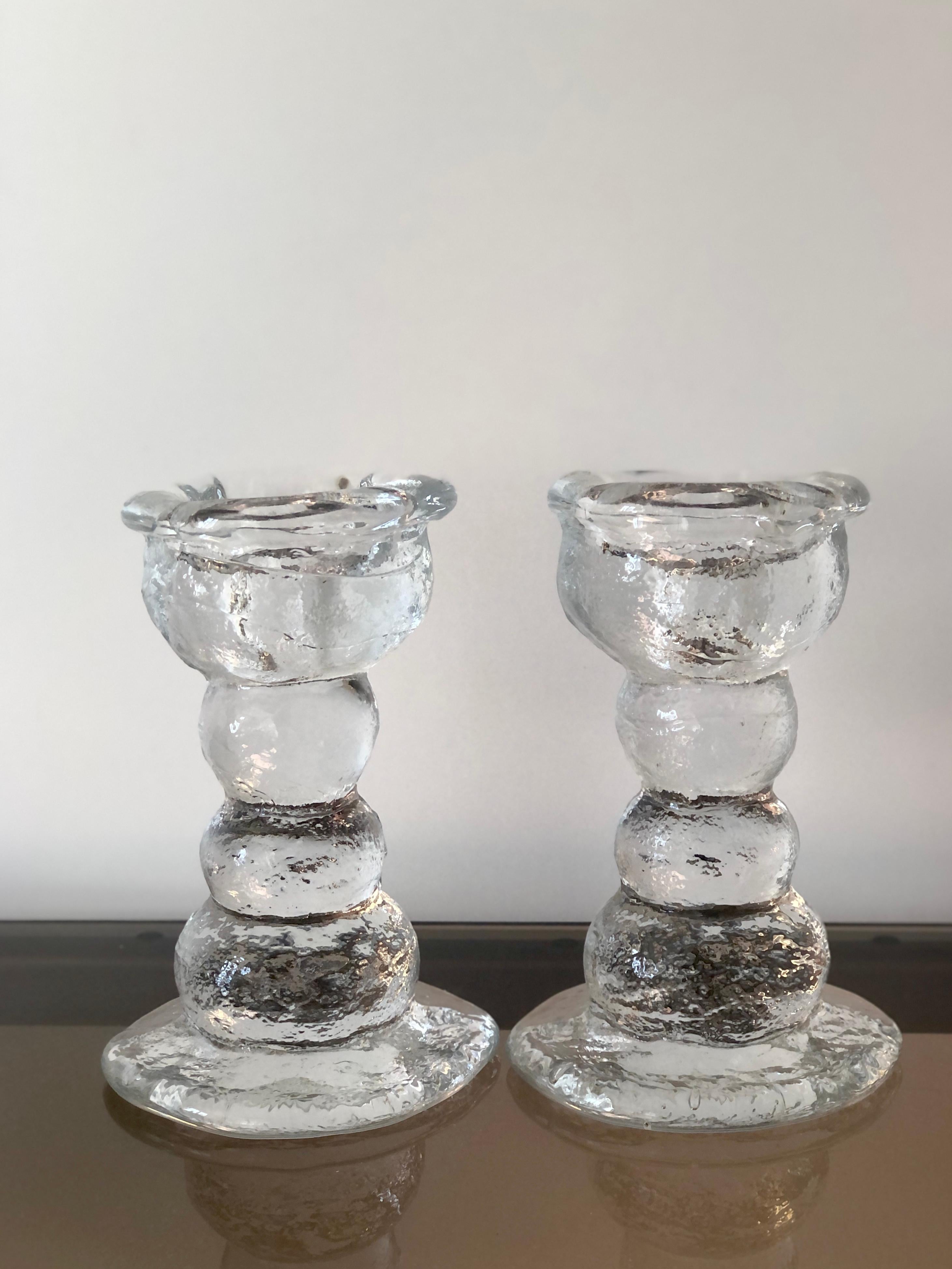 Mid Century Modern 1970s brutalist designed Candlesticks designed by Pertti Santalahti for Humppila Finland. Very heavy and robust. 
Clear glass, fitting long candles or tealights.
Measures: H 17 cm D 12 cm to base.