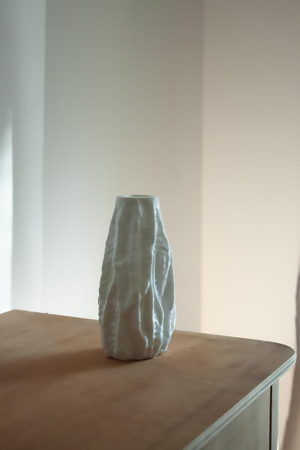 This milk glass vase is in a Brutalist design and was made in Germany around 1970. Its surface is reminiscent of ice or bark, giving this vase a highly textured and interesting surface. This vase, while having a rather tough-looking design, still