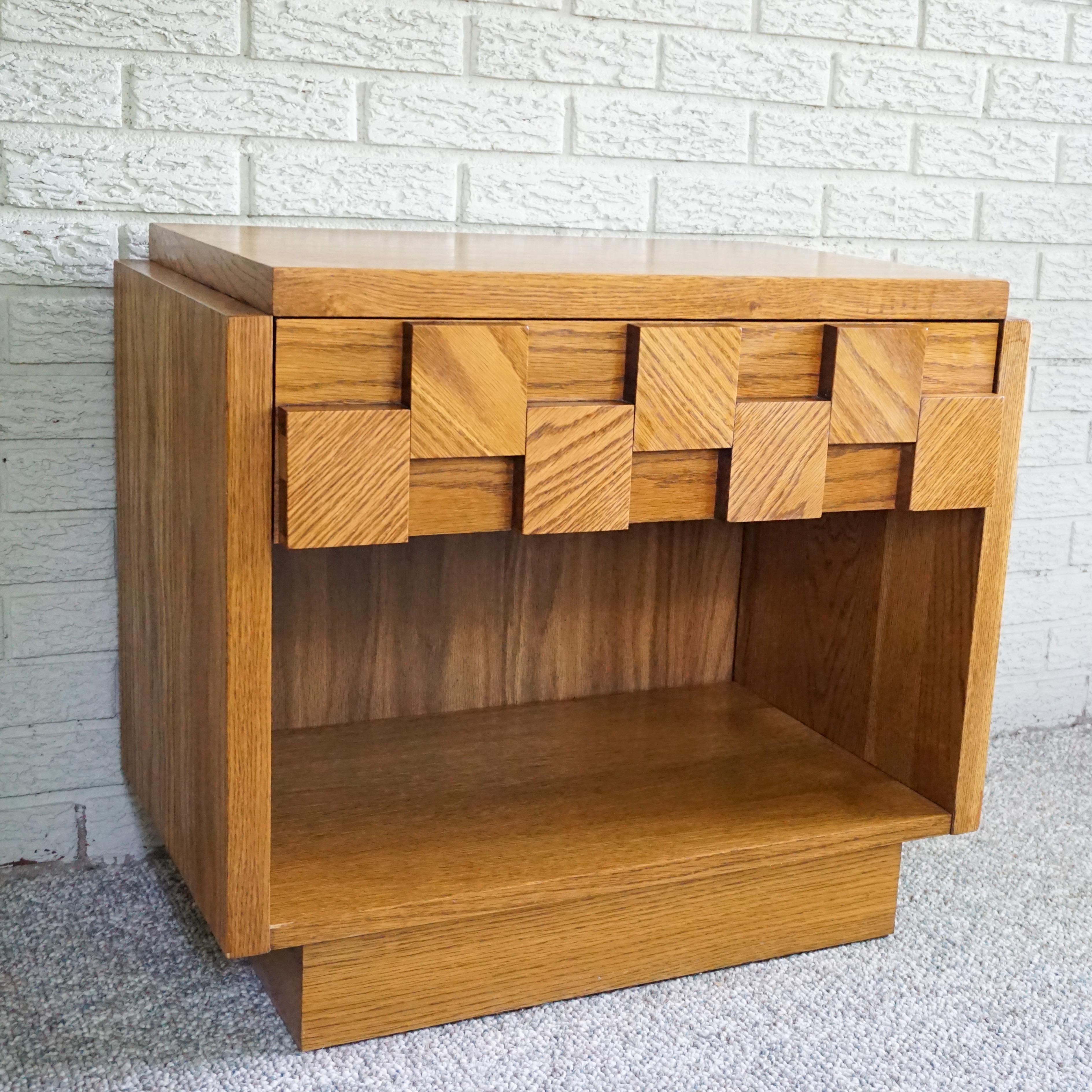 Brutalist style nightstands by Lane from their 1970s Staccato furniture line. The front of the chest is done in a mosaic sculptural pattern of oak blocks on the drawer fronts. Beneath the drawer is open storage space. It retains the original deep