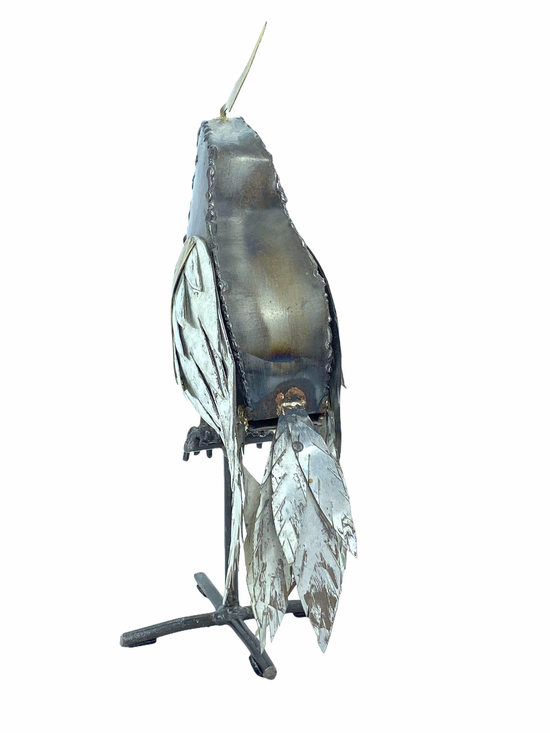 Brutalist parrot sculpture in the style of Sergio Bustamante or Alexander Blazquez. 
Handcrafted and welded out of different colored metals. Perched parrot on metal stand.
Ideal size for bookcase/etagere styling.Perfect gift idea for the