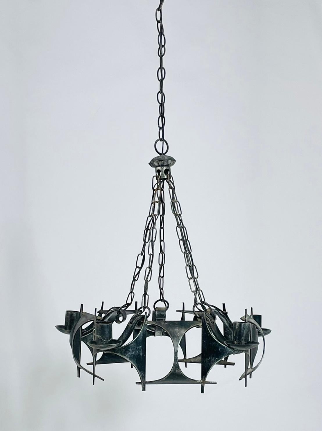 A striking Brutalist Modernist chandelier handcrafted in wrought iron, dating from the 1970s. This sculptural fixture features bold geometric panels and sweeping curves that embody the raw, expressive character of Brutalist design.

Suspended from