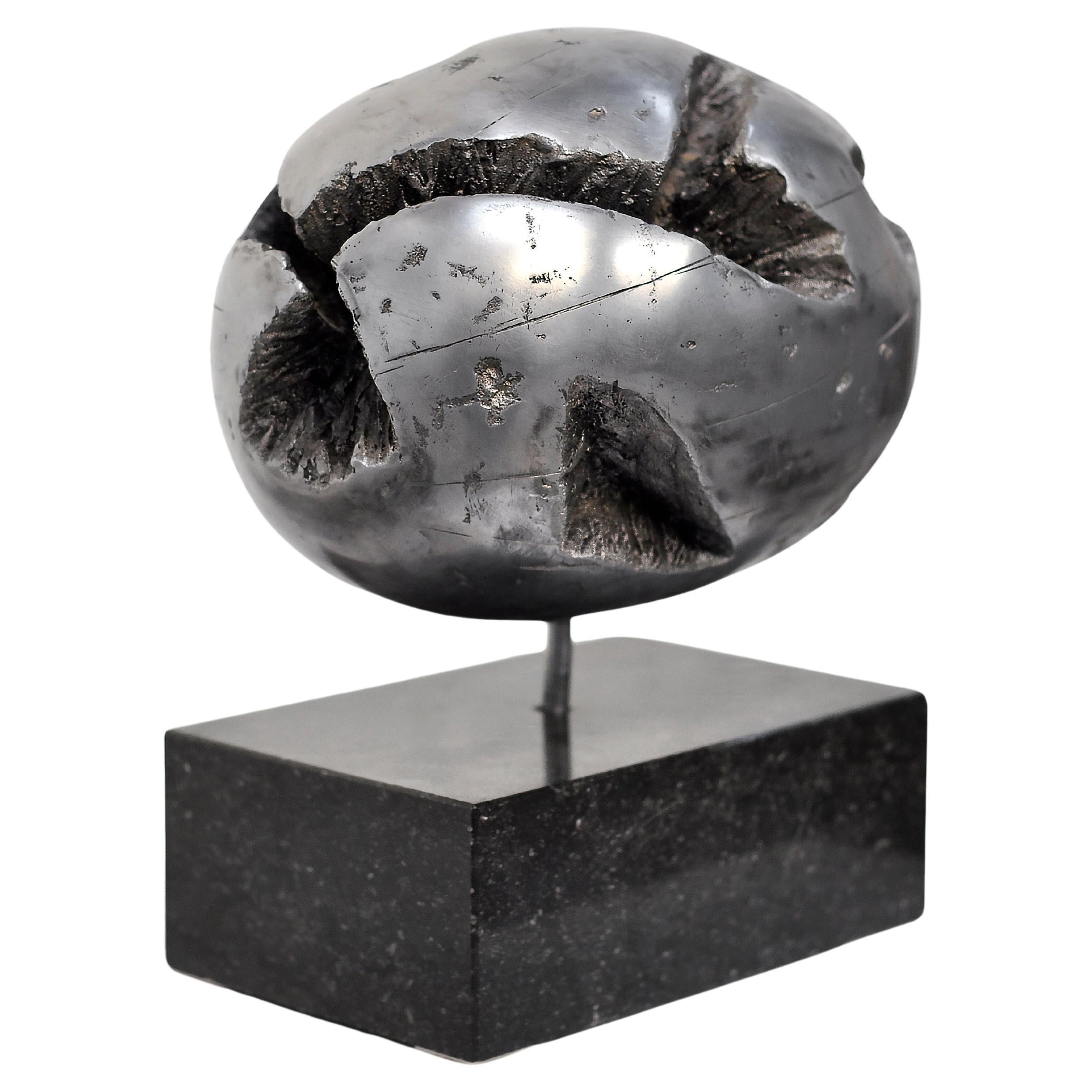 This striking Brutalist metal sculpture from the 1970s embodies the raw, expressive aesthetic of the movement. Crafted from polished cast metal, the piece features a cracked spherical form. The cracks reveal rugged textures within, contrasting with