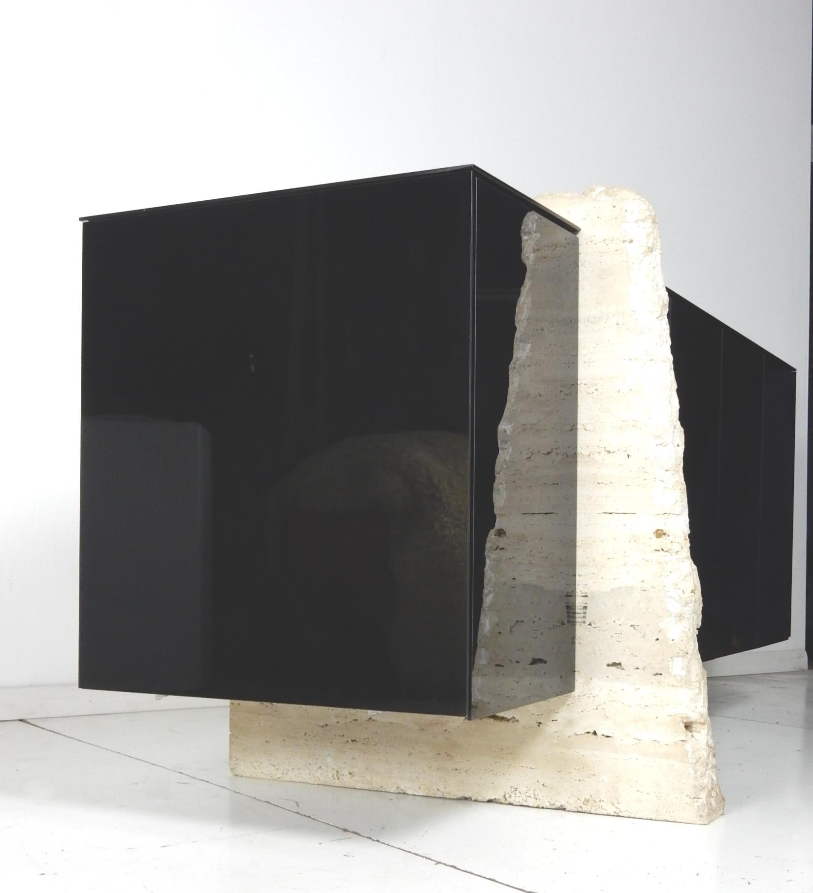 Stunning black glass veneer credenza supported on a massive Travertine slab
slicing through the end cabinet with a centre kickstand slab on the long end.
5 push click cabinet doors total, 4 on the long side open to 2 large open shelf
