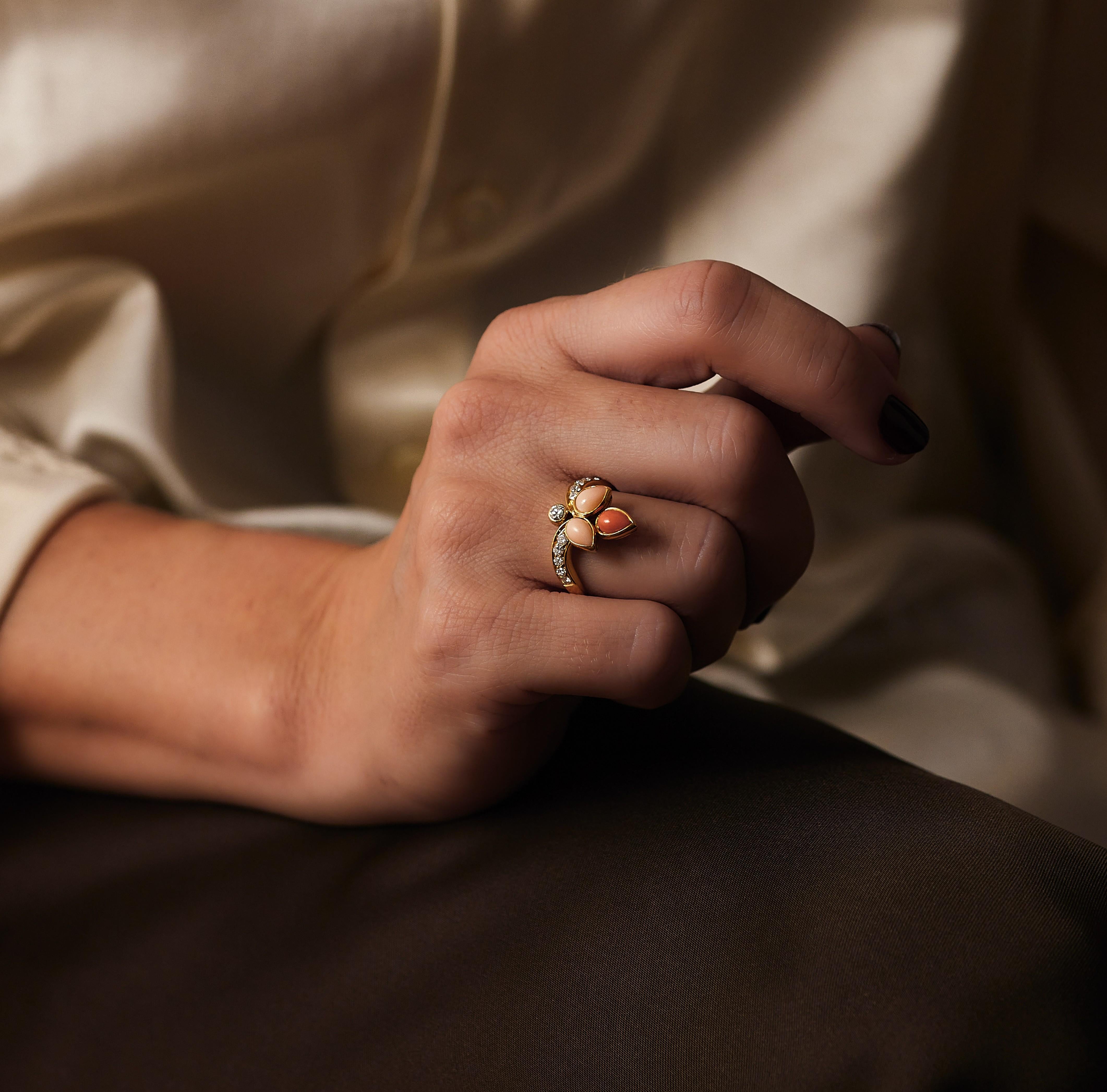 Bulgari-Ring mit Diamanten und Korallen aus den 1970er Jahren.

Eine stilisierte Korallenpalmette, drei Korallenblätter - zwei helle Engelshautfarben, ein orangerotes. Der Ring ist aus 18 Karat Gelbgold gefertigt und mit ca. 0,4 Karat Diamanten im
