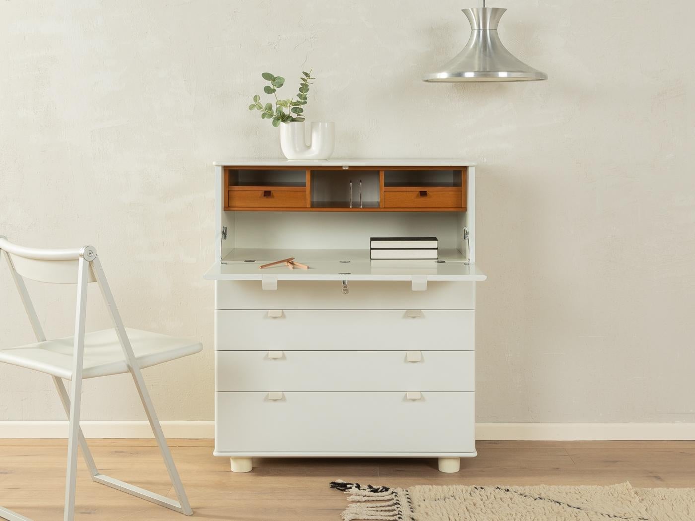 Wonderful bureau from the MUTARO line designed in 1979 by Peter Maly for interlübke. Corpus in white lacquered wood with four drawers, a hinged work surface, two internal drawers, a storage compartment and round plastic legs.

Quality Features:
   