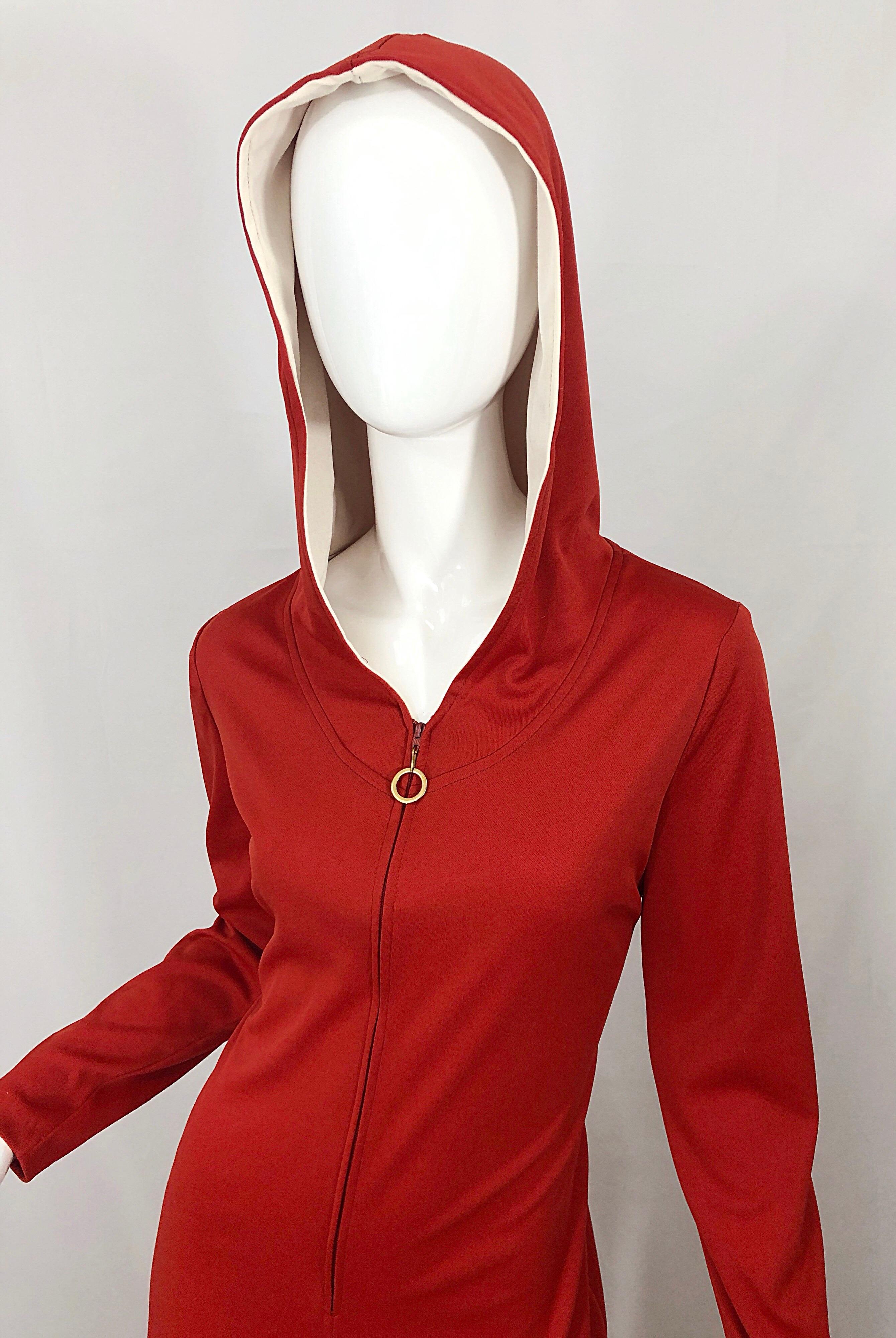 Awesome mid 1970s burnt orange wide leg hooded jumpsuit! Features a hidden zipper up the front with a doorknob pull. Soft stretch jersey fabric can accomodate an array of sizes. Great belted or alone with wedges, sandals, boots or heels. 
In great