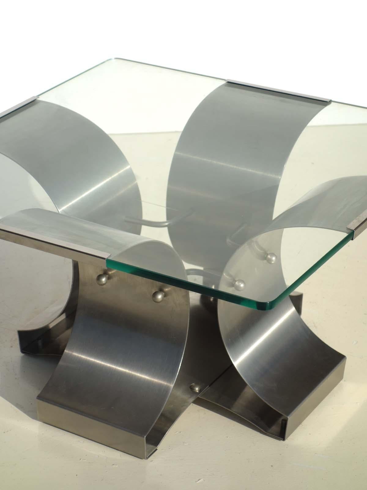 Coffee table designed by Francois Monnet, France, 1970s. 
The brushed stainless steel frame is topped with a glass top, which is surrounded and edged with metal clips.