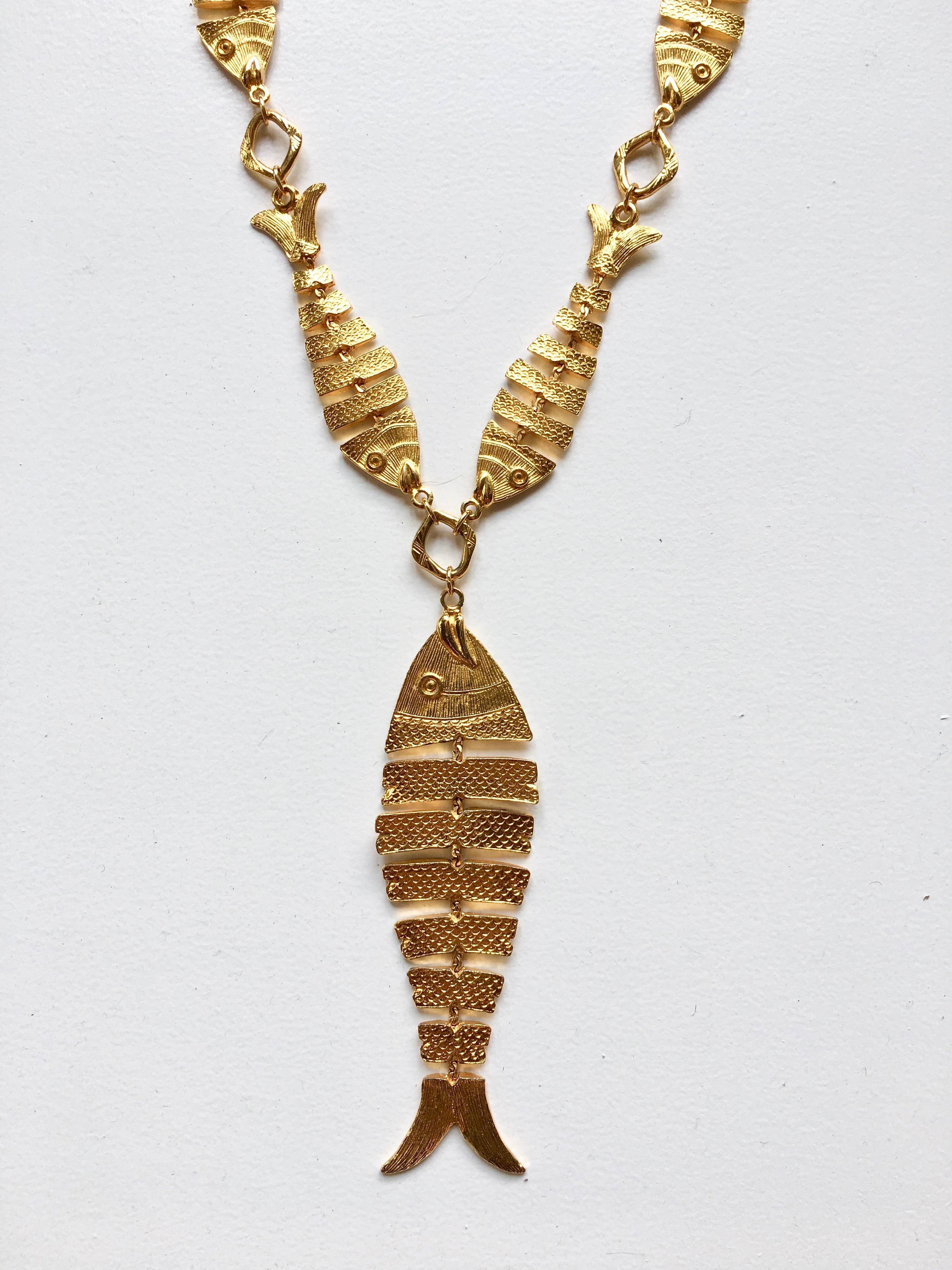 This is a super fun piece made by Cadoro in the 1970s. It features a necklace made up of articulated gold-tone fish with a larger articulated gold-tone fish pendant hanging from it. The necklace without the pendant measures 28 1/2 inches long. The