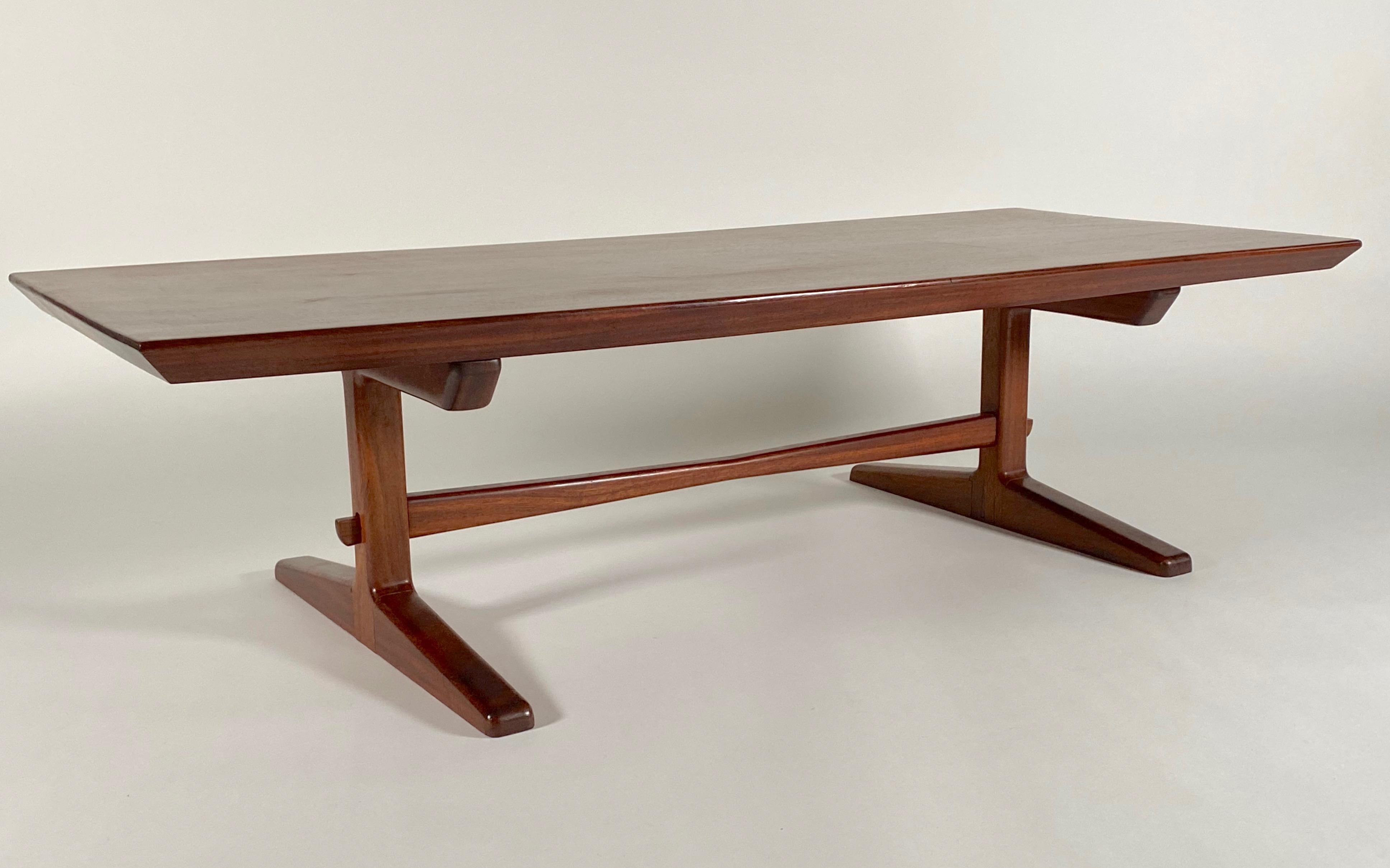 Studio made circa 1970s solid mahogany coffee with trestle legs and a beveled edged top with two butterfly repairs to the underside, a stretcher bar underneath adds support and form to the table. Richly grained and colored mahogany, this is a very
