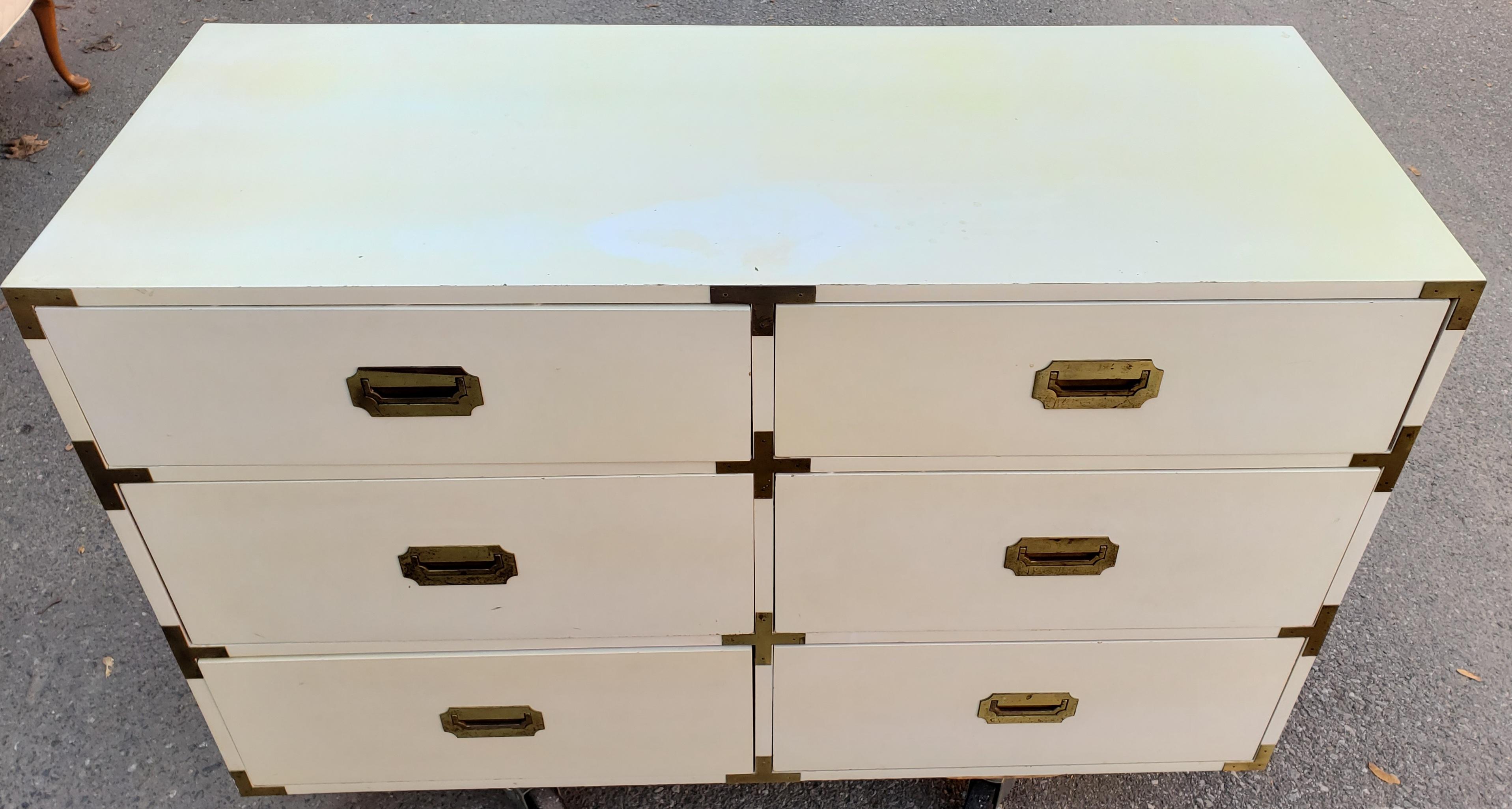 This 6-drawer campaign chest was part of the Swingers Collection by Schoolfield Industries, circa 1970s. It has an antique white paint satin finish with brass hardware. All of the hardware is original and showing some signs of aging appropriate with
