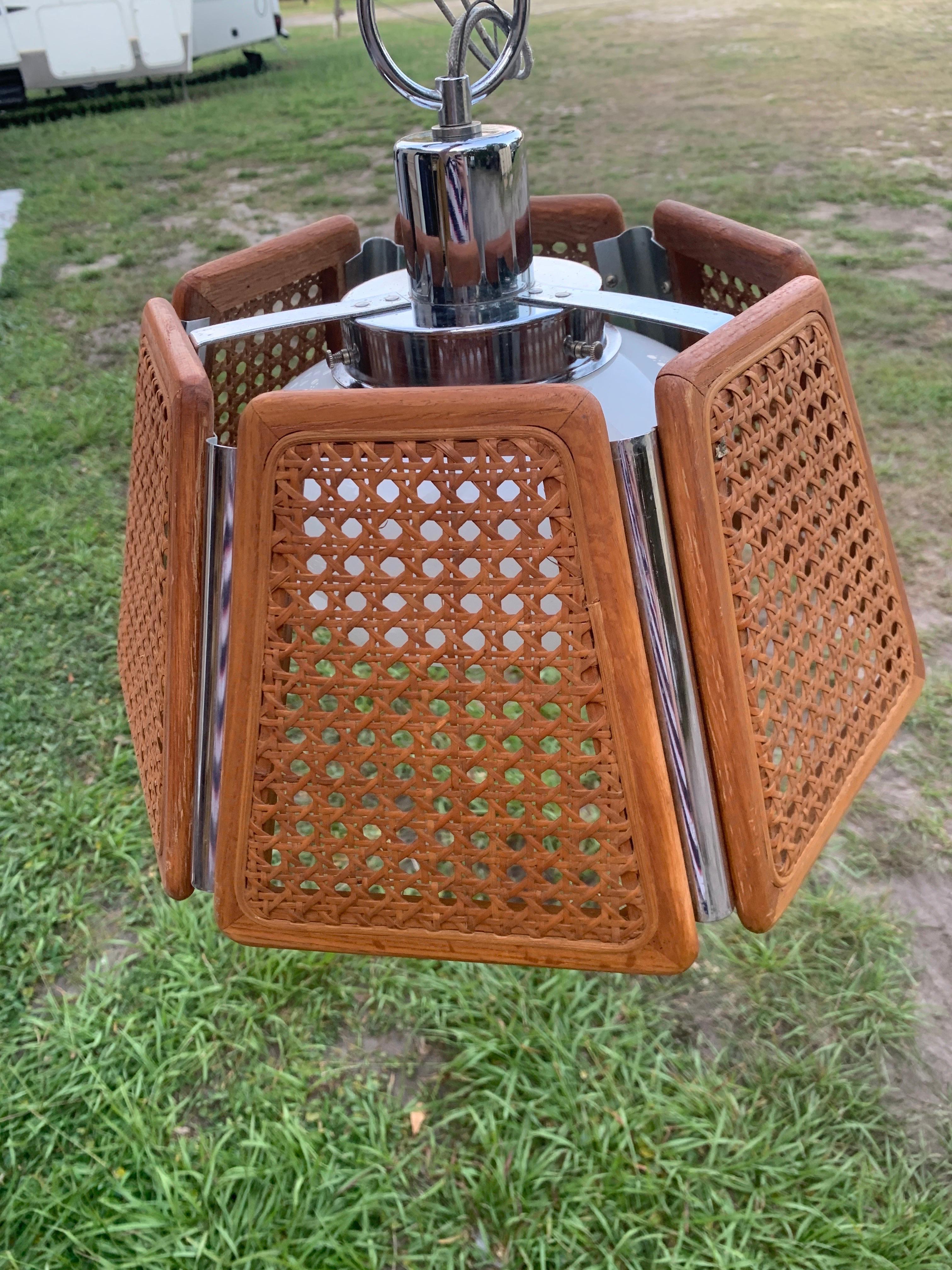 1970s cane and wicker light fixture with chrome accents. The chain on this piece is rather short, about 18 inches in length. Could possibly use a rewiring, however it was in working condition when removed. No major damages to note. 