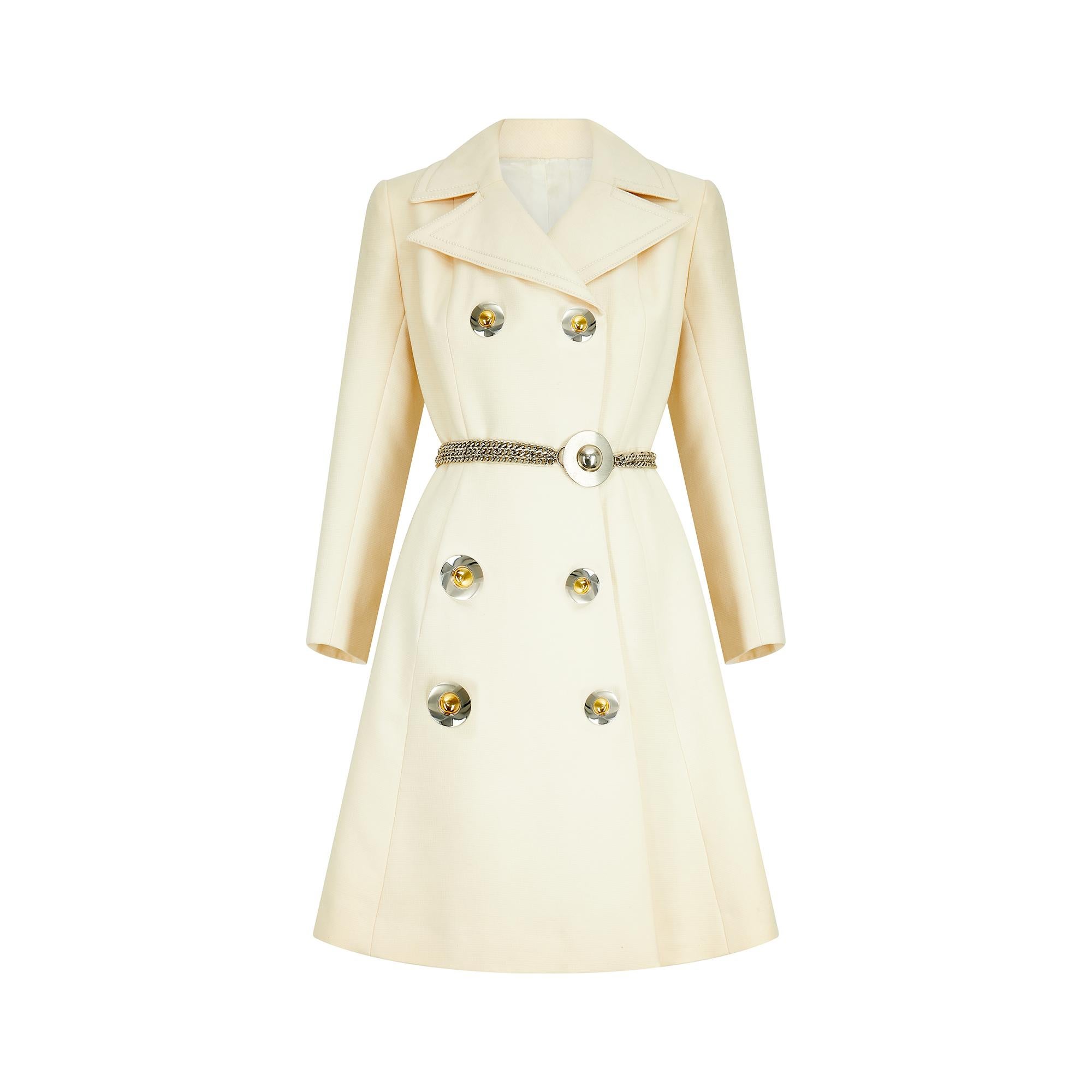 Unmarked, but possibly attributed to Pierre Cardin, this double-breasted coat features the space age detailing the Italian-French couturier was known for.  Classically A-line tailored from cream wool with a bold tonal running stitch which edges the