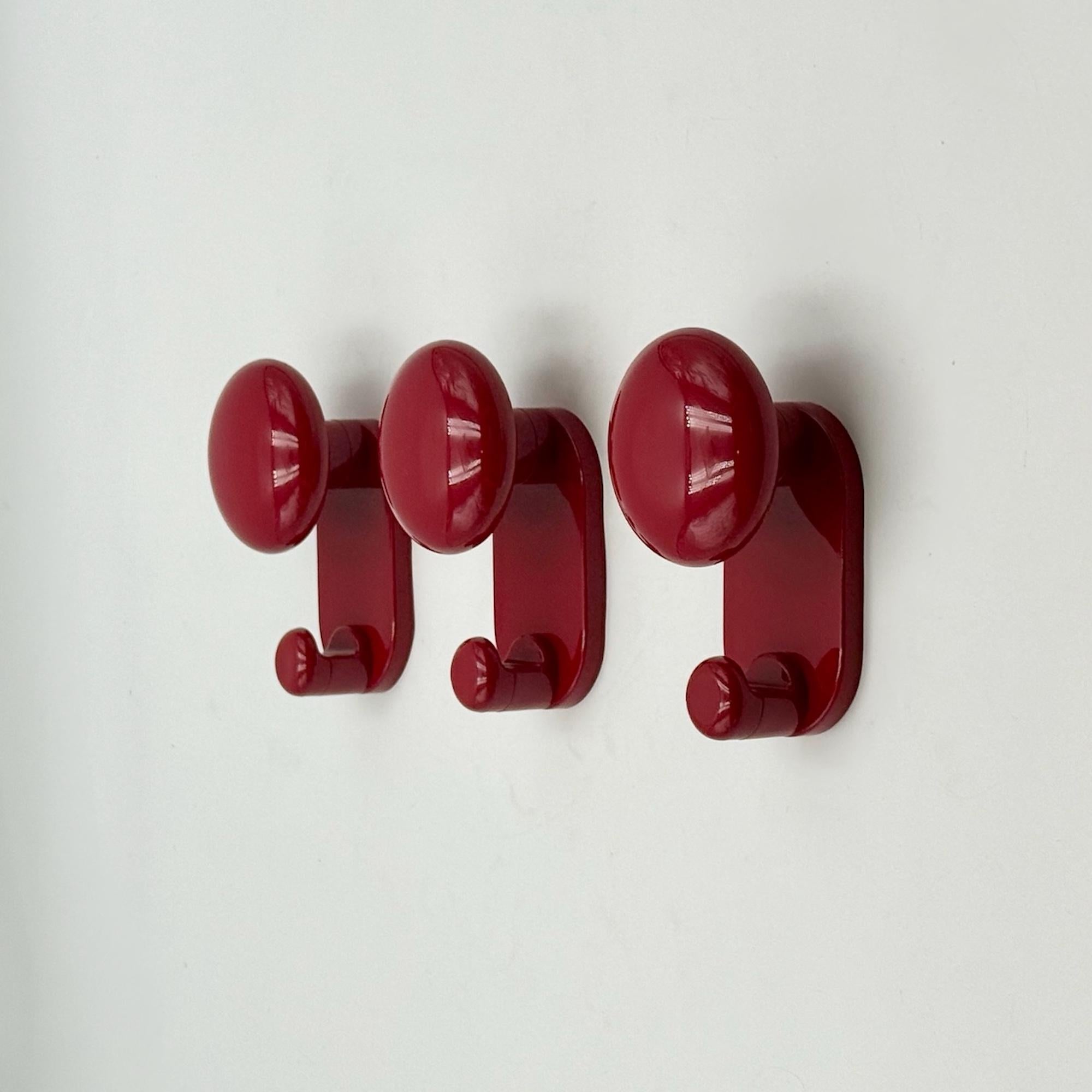 This rare set of vintage modernist wall hooks was designed by Carlo Bartoli and produced in Italy by Con&Con during the late 1960s–70s. Each hook is formed from glossy burgundy red plastic, with a sculptural round knob and integrated hanging