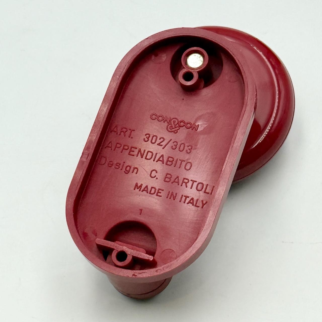 This rare set of vintage modernist wall hooks was designed by Carlo Bartoli and produced in Italy by Con&Con during the 1970s. Each hook is formed from glossy burgundy red plastic, with a sculptural round knob and integrated hanging element. The