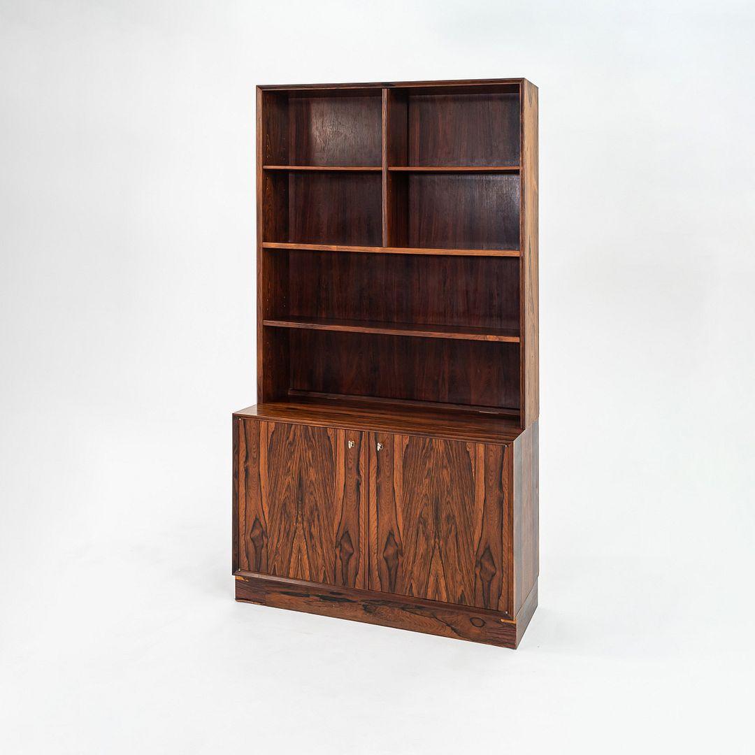 This is a 1970s Danish Rosewood Cabinet with a coordinating Bookcase Hutch by Carlo Jensen for Poul Hundevad. The top and sides of the piece feature a rich rosewood veneer exterior. At the bottom of the piece, there are two doors that open to reveal