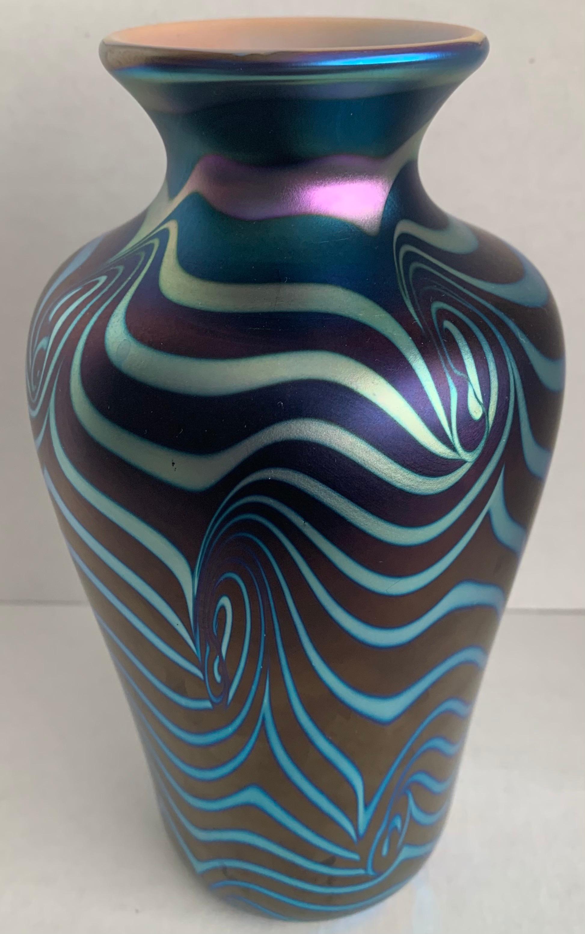 1977 Carlson blown glass lustre vase. Iridescent dark blue background with green lustre swirls throughout. Etched signature on the underside.