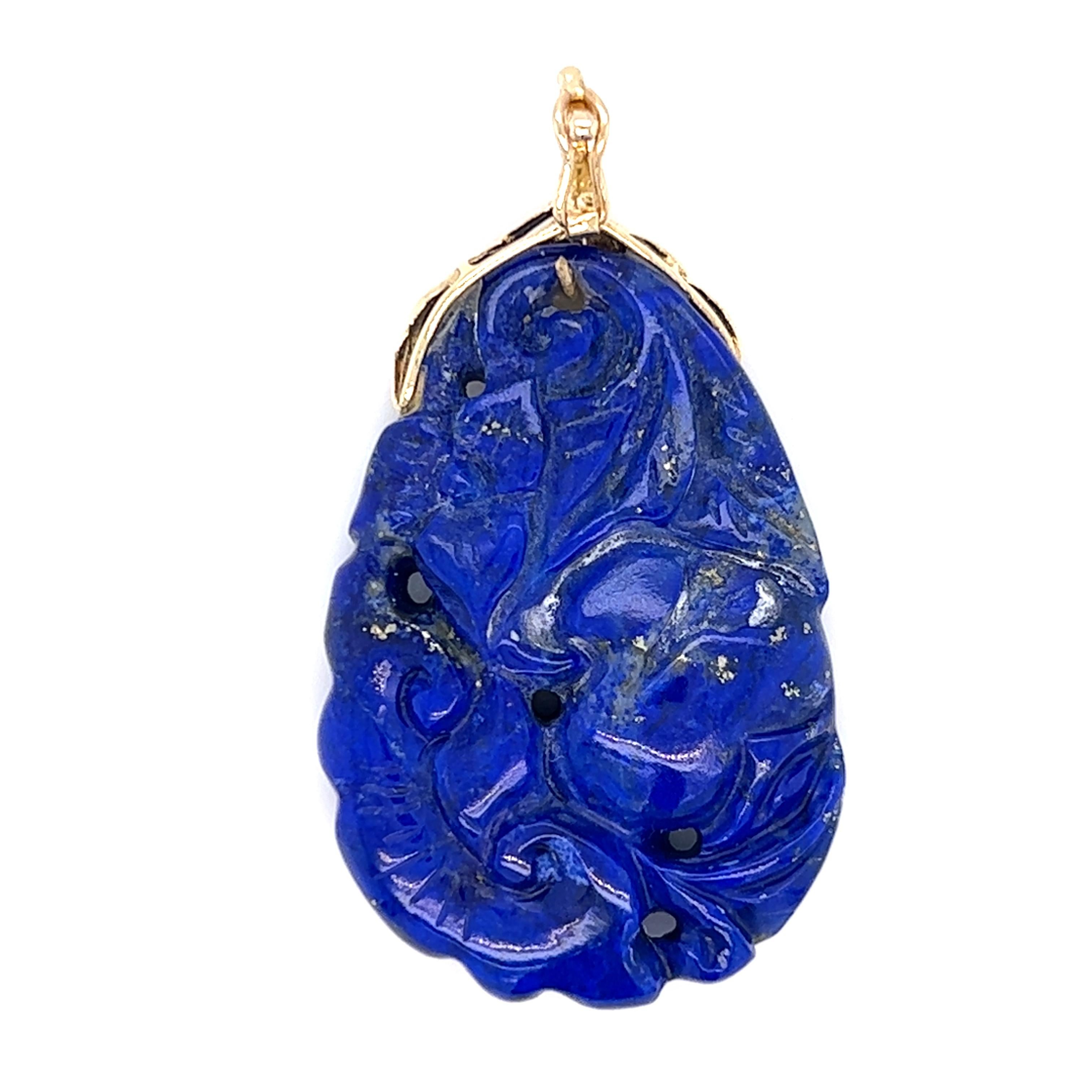 One carved lapis lazuli pendant set with one 14-karat yellow gold enhancer bail.  The pendant measures 1.5 long and one (1) inch wide.  