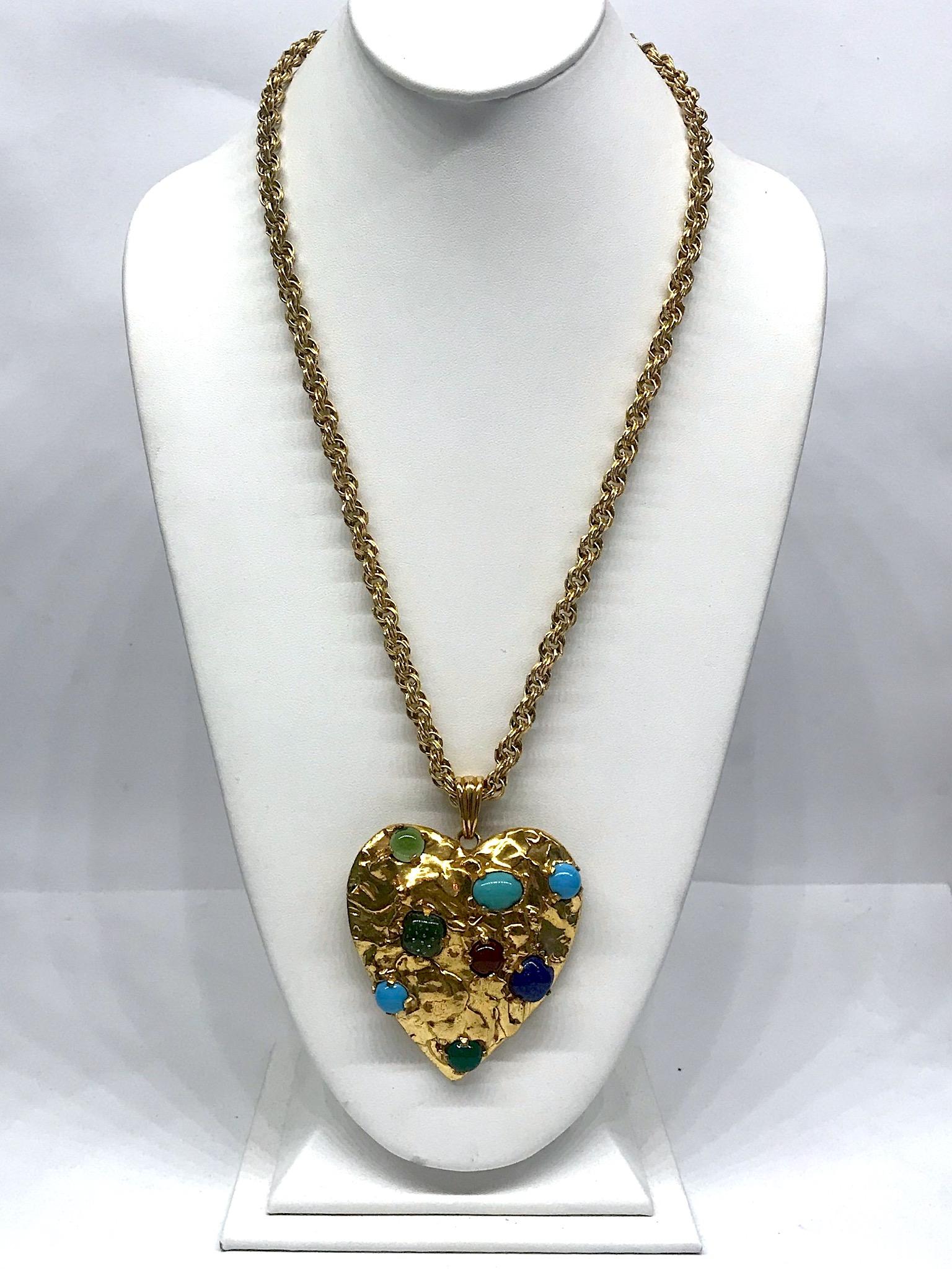 A sculptural large heart pendant necklace by American fashion jewelry company Castlecliff. The large heart is cast with a rough gold nugget texture. It is gold plated and set with eight glass cabochons in translucent green,  turquoise color,  jade