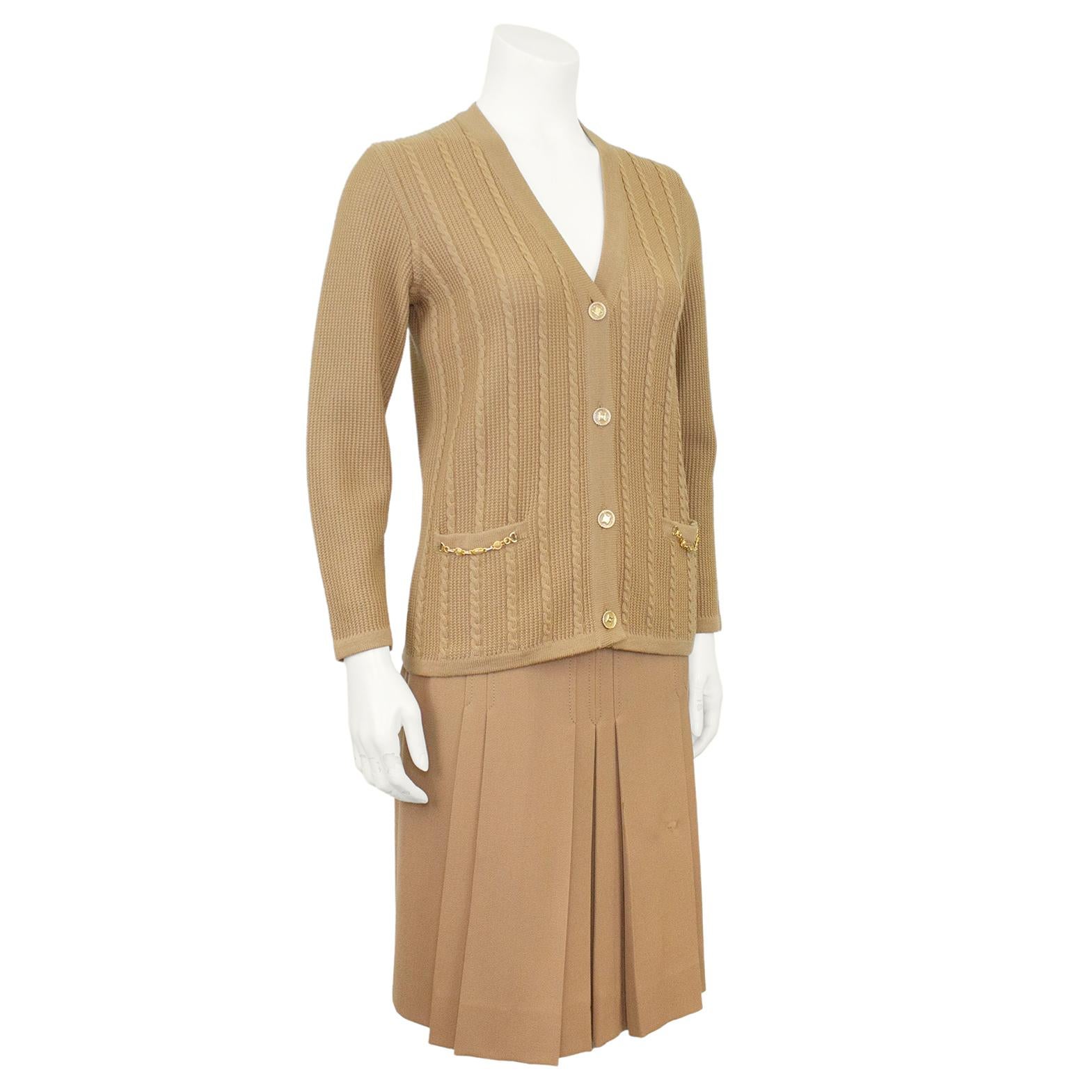 Classic and timeless Celine 100% wool beige cardigan and matching gabardine skirt ensemble from the 1970's. The set features a cable knit and waffle cardigan with gold tone metal and cream enamel chain accents at the pockets. Beautiful gold tone and