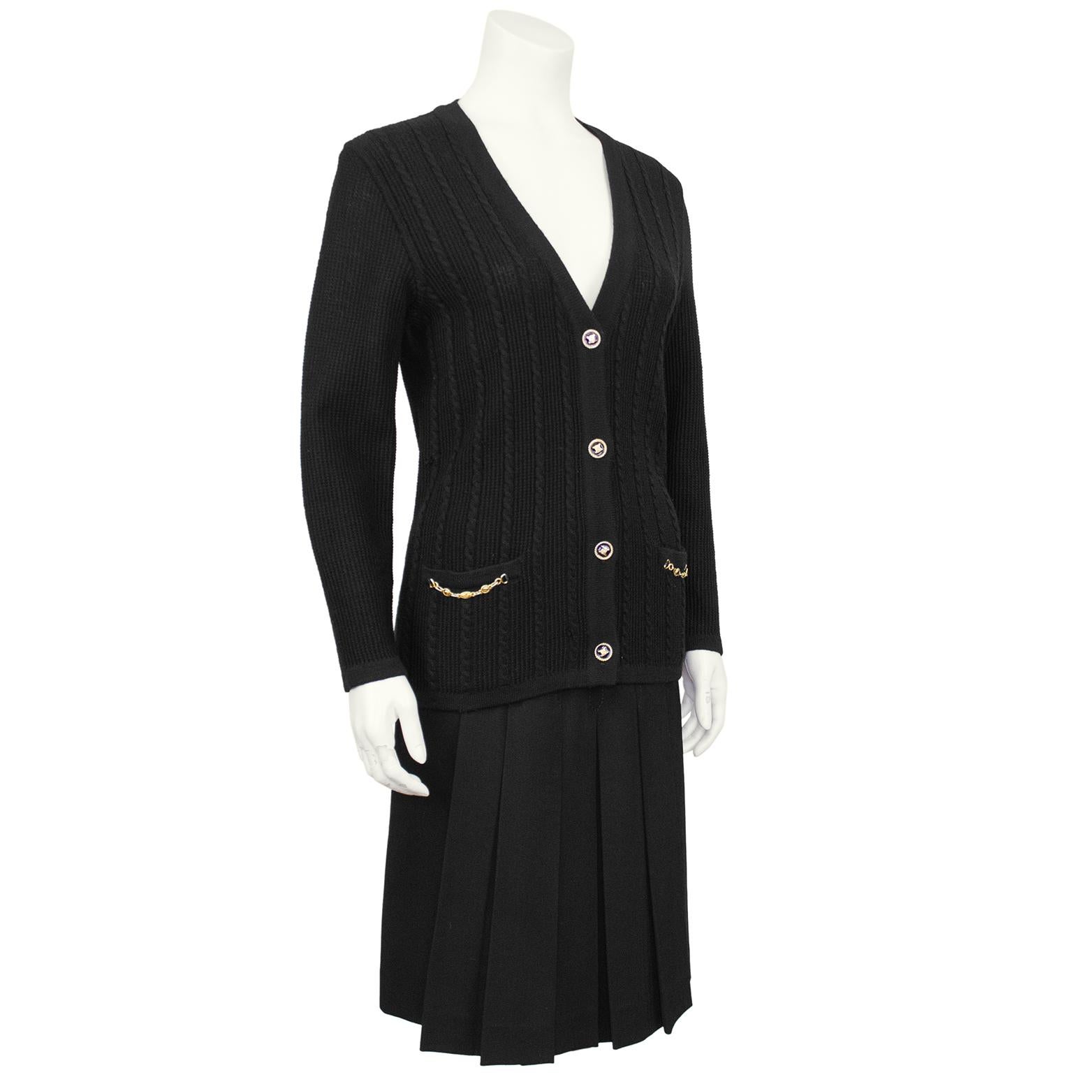 Classic and timeless Celine 100% wool black cardigan and gabardine skirt ensemble from the 1970's. The set features a cable knit and waffle v neck cardigan with gold tone metal accents. Slit pockets at the hips with chain details and beautiful gold