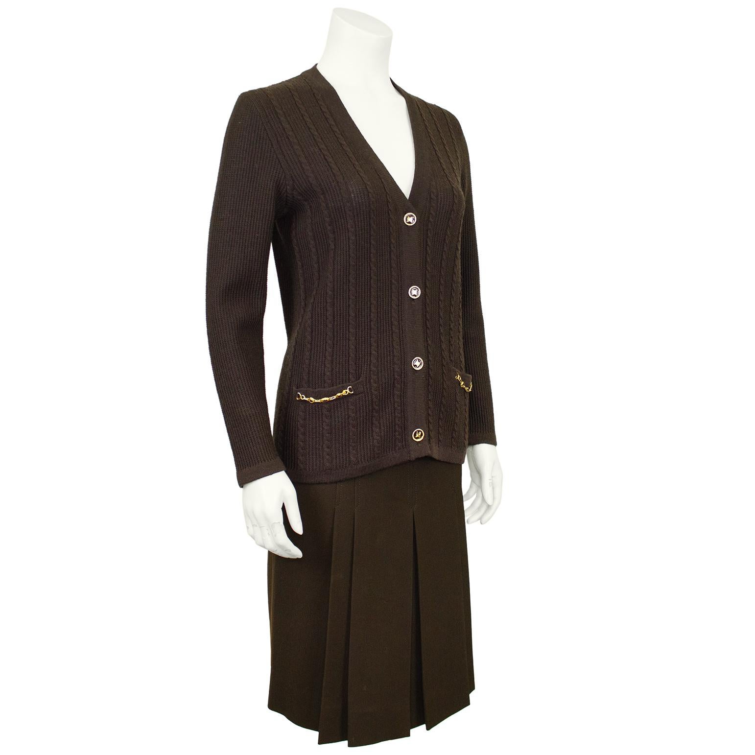 Classic and timeless Celine 100% wool chocolate brown cardigan and matching gabardine skirt ensemble from the 1970's. A cable knit cardigan with gold tone metal chain accents at the pocket and beautiful gold tone and brown enamel logo buttons. The