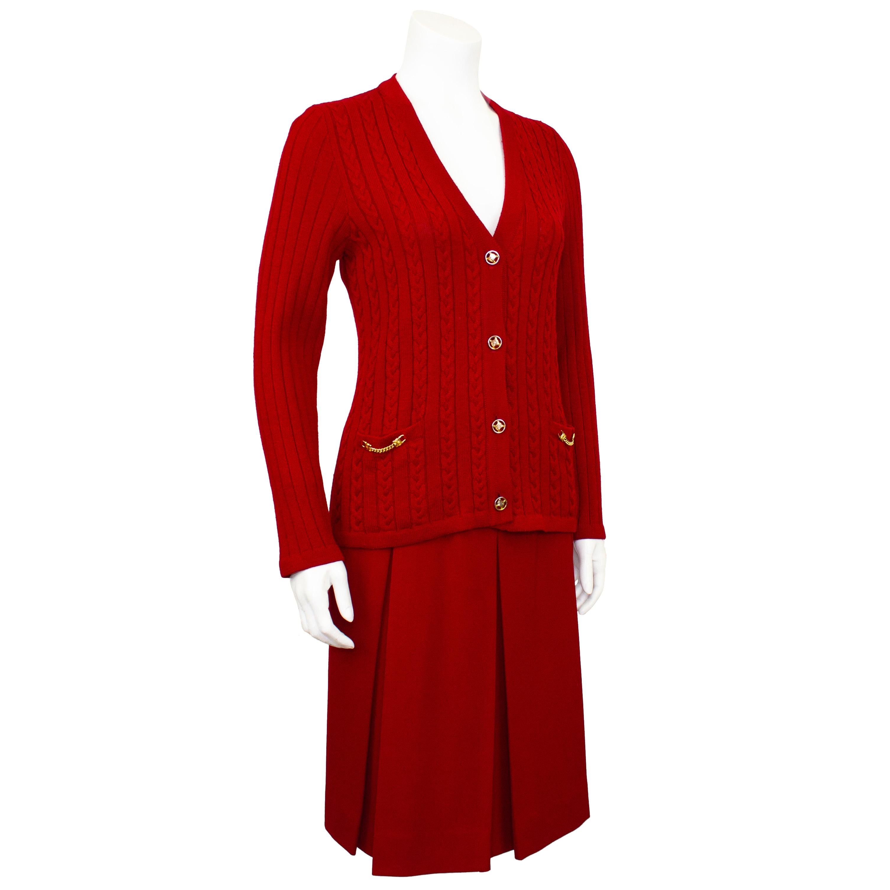 Classic French girl style - Celine 100% wool crimson red cardigan and matching gabardine skirt ensemble from the 1970's. The set features a cable knit cardigan with gold tone metal chain details at the pockets and Celine logo buttons. The pleated