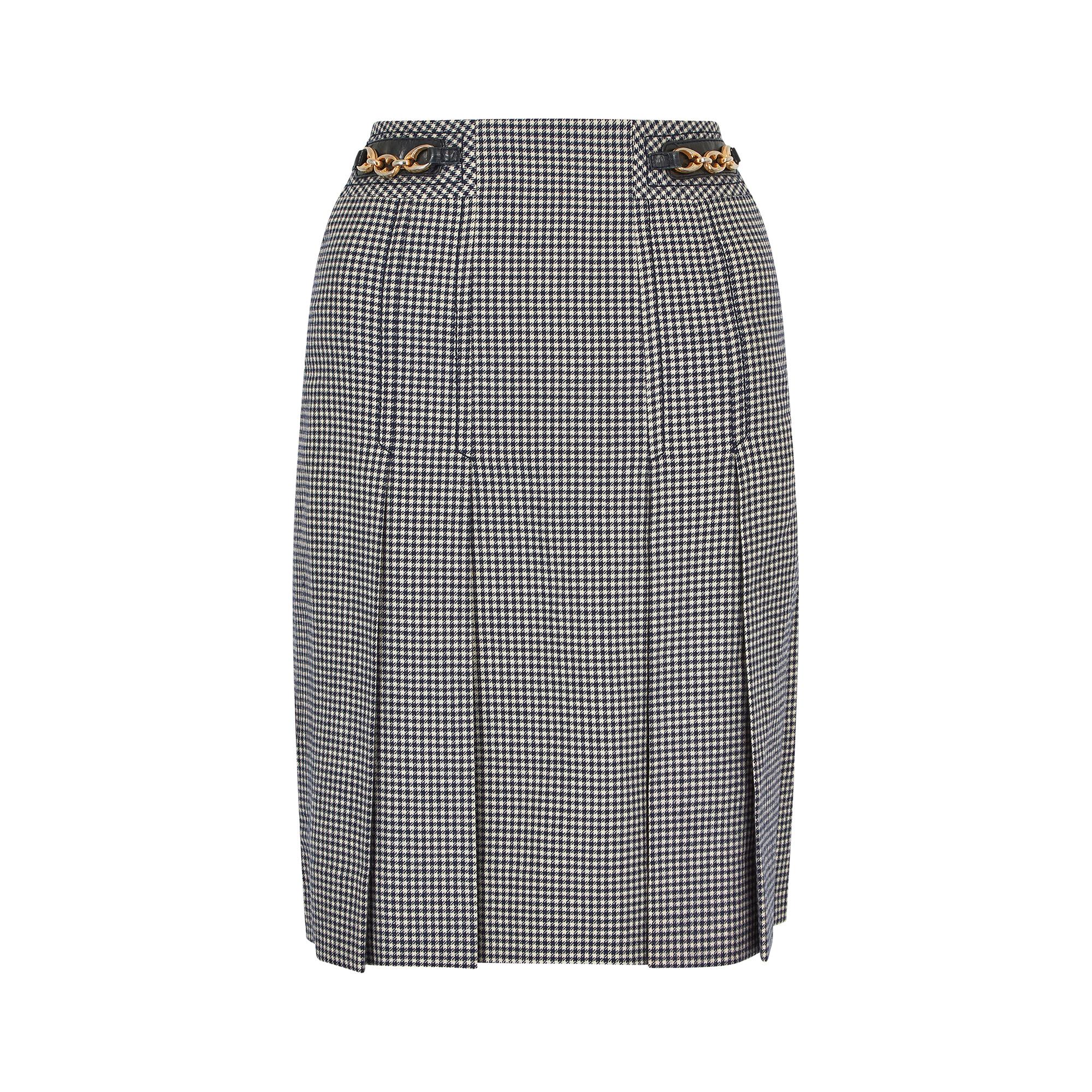 Early 1970s Celine 100% wool classic box pleat skirt.  This is a high-waisted navy and white houndstooth design with navy calfskin leather and gold tone chain link gourmette either side of the waist band.  Fully lined in a quality navy acetate and