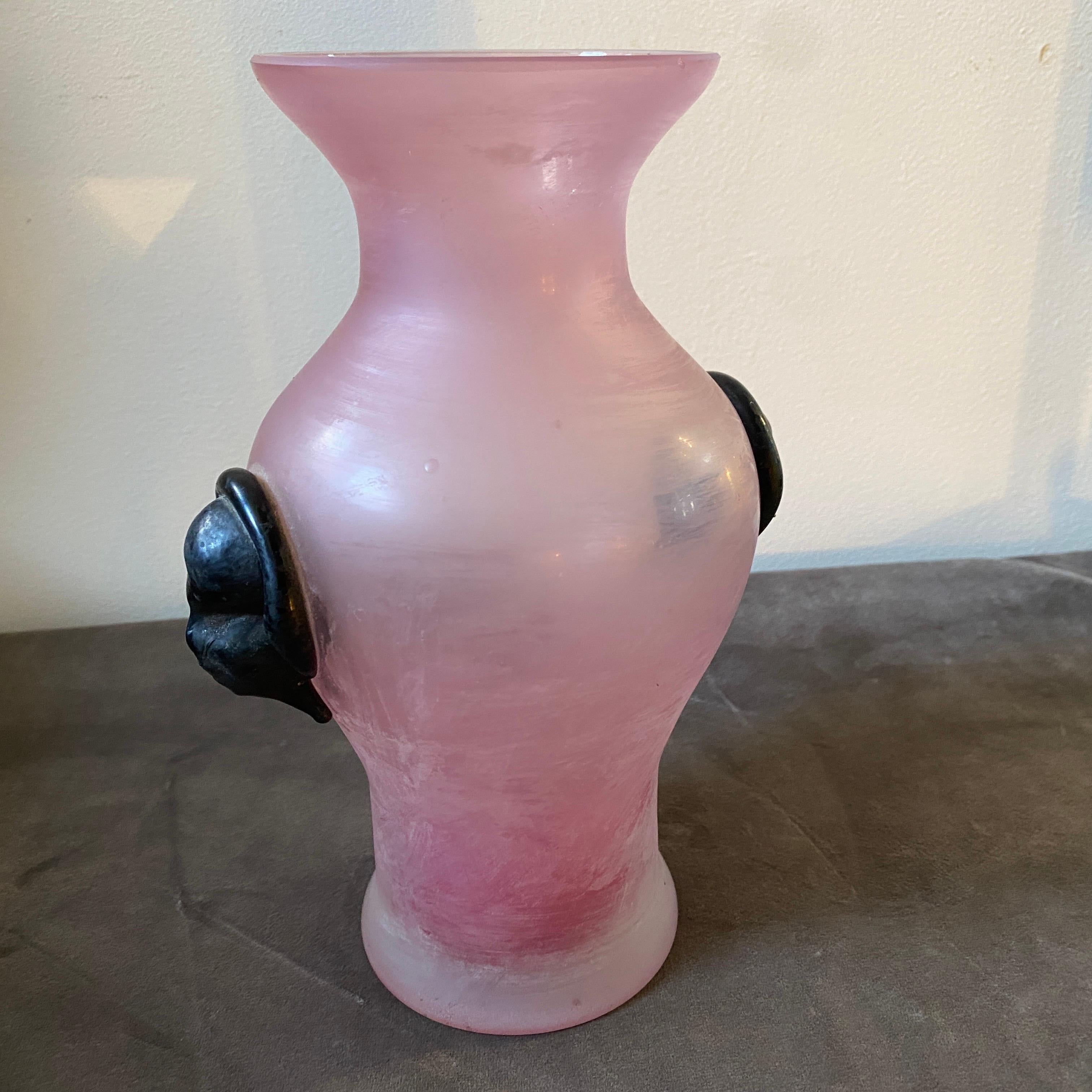 An high quality pink scavo murano glass vase with two applied black glass masks attributed to Cenedese. It's in perfect conditions. Crafted from Murano glass, known for its exceptional clarity, purity, and vibrant colors. The Scavo technique