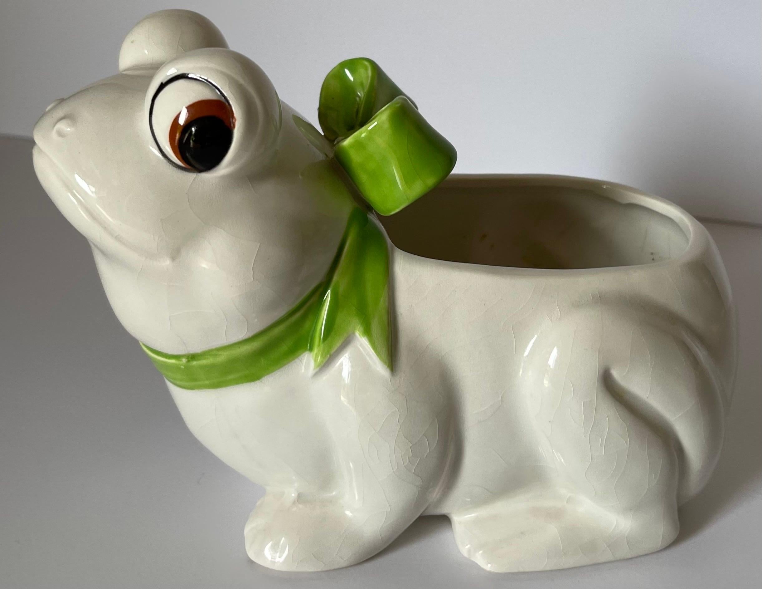 Whimsical 1970s ceramic frog ceramic planter. Cream colored glazed frog with lime green ceramic bow. No makers mark or signature.