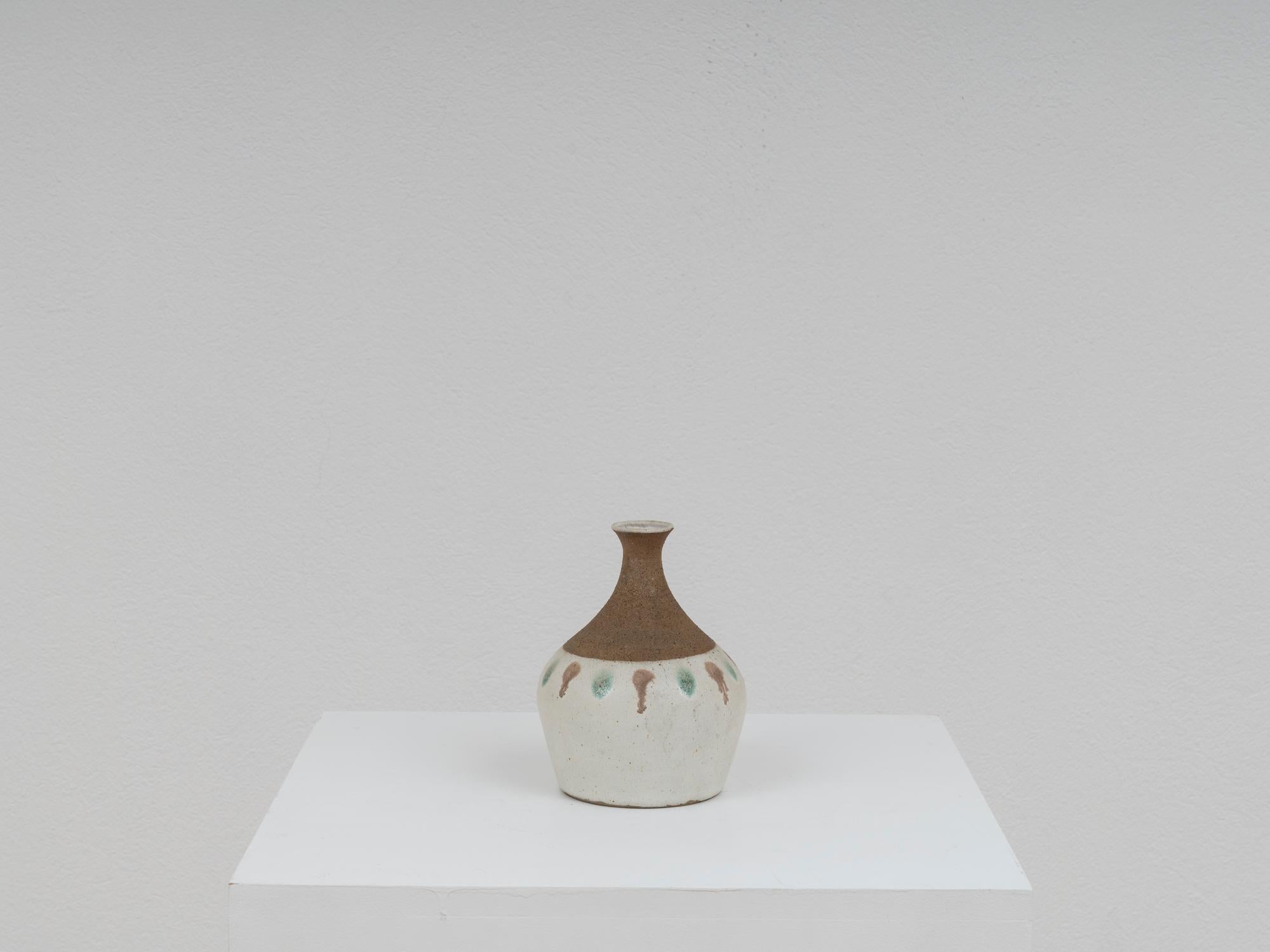 Charmante Vase des Keramikmeisters Bruno Gambone aus den 1970er Jahren. Sie ist in Erdtönen mit einem Hauch von Türkis gehalten und hat eine fühlbare Oberfläche, die am Hals rau und am Boden glatt ist.
Das Stück bleibt in sehr gutem Vintage-Zustand.