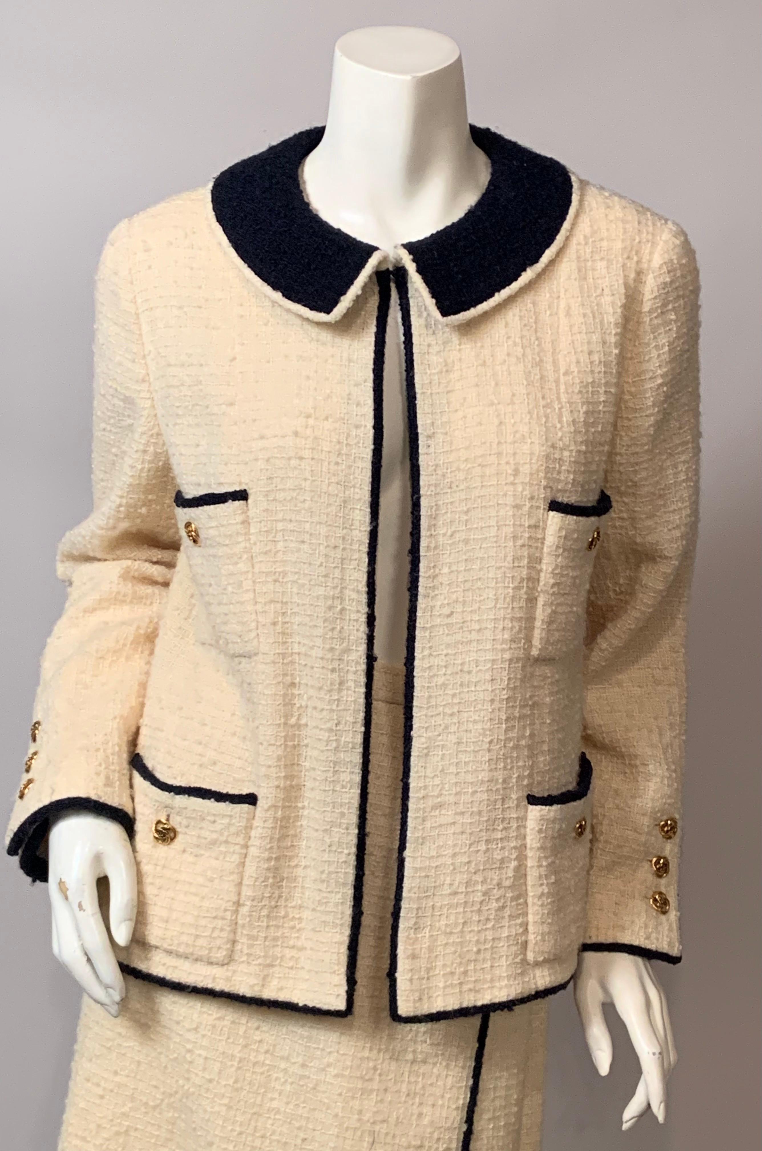 Questo tailleur con gonna in lana boucle color crema di Chanel degli anni '70 è rifinito con lana boucle blu navy. Il colletto, i polsini, le tasche centrali e l'orlo sono rifiniti in lana bouclé blu navy.  Le quattro tasche, due sul petto e due sui