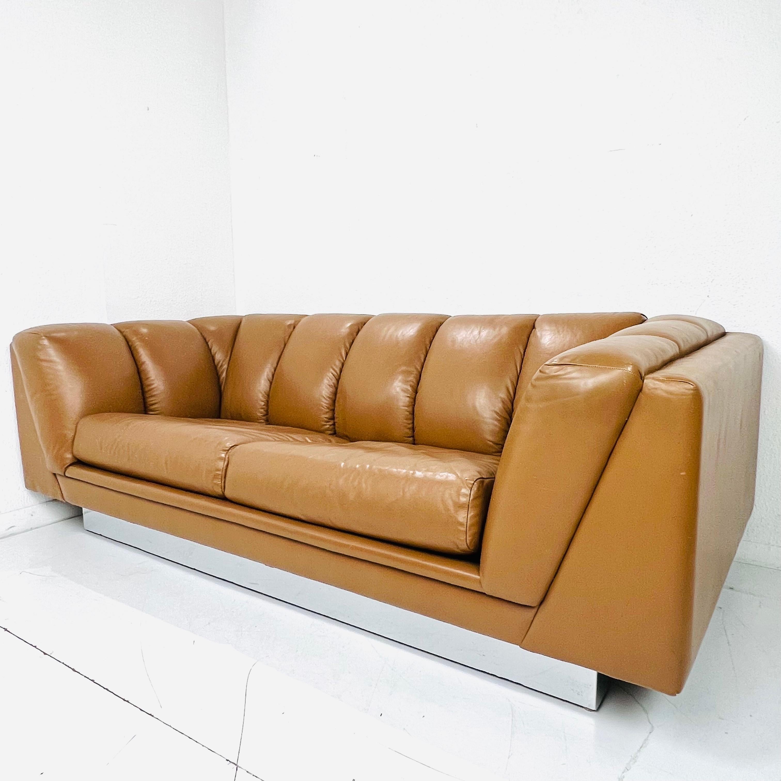 Handsome channeled leather sofa with chrome base by San Francisco, CA-based Metropolitan Furniture, c.1970s. The sofa features a polished mirrored chrome base that gives it a floating effect. The cushions and frame feature the original leather