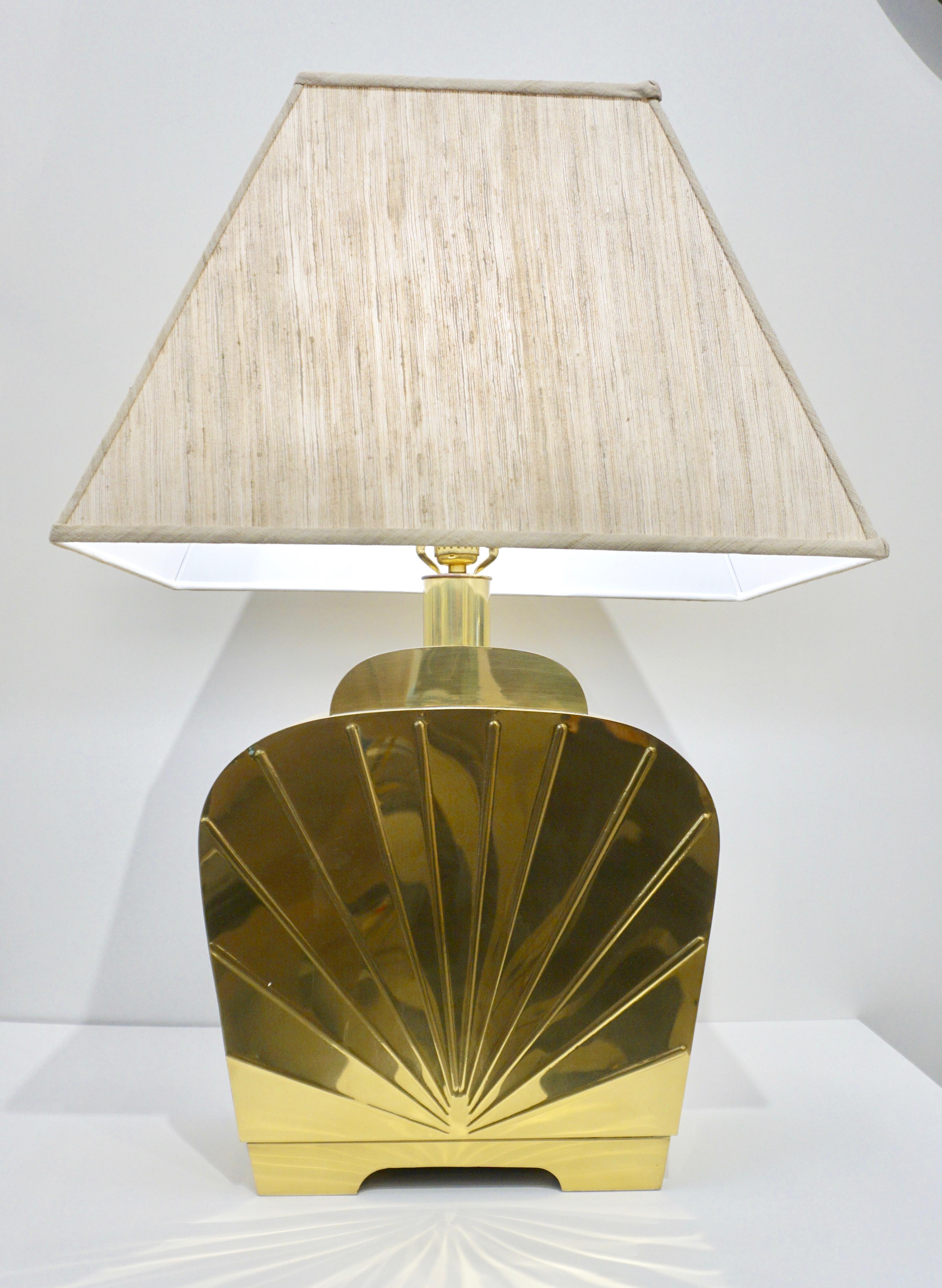 A very chic vintage pair of glamorous American Hollywood Regency table lamps. Exquisite high quality of execution in handcrafted shiny gold heavy solid brass, the streamline organic shape is elegantly decorated with an Art Deco style cast decor in